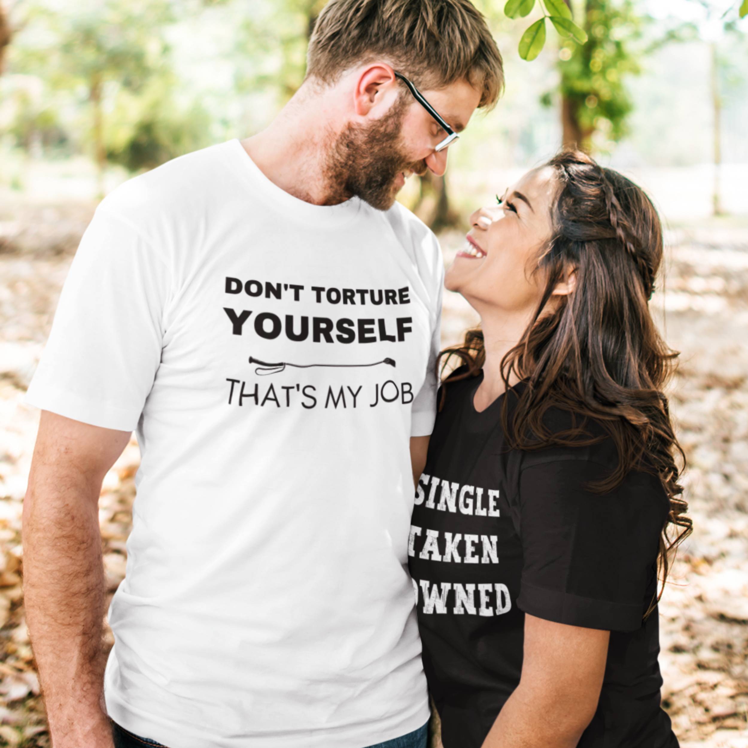 Man and woman standing close together, both wearing t-shirts with text.