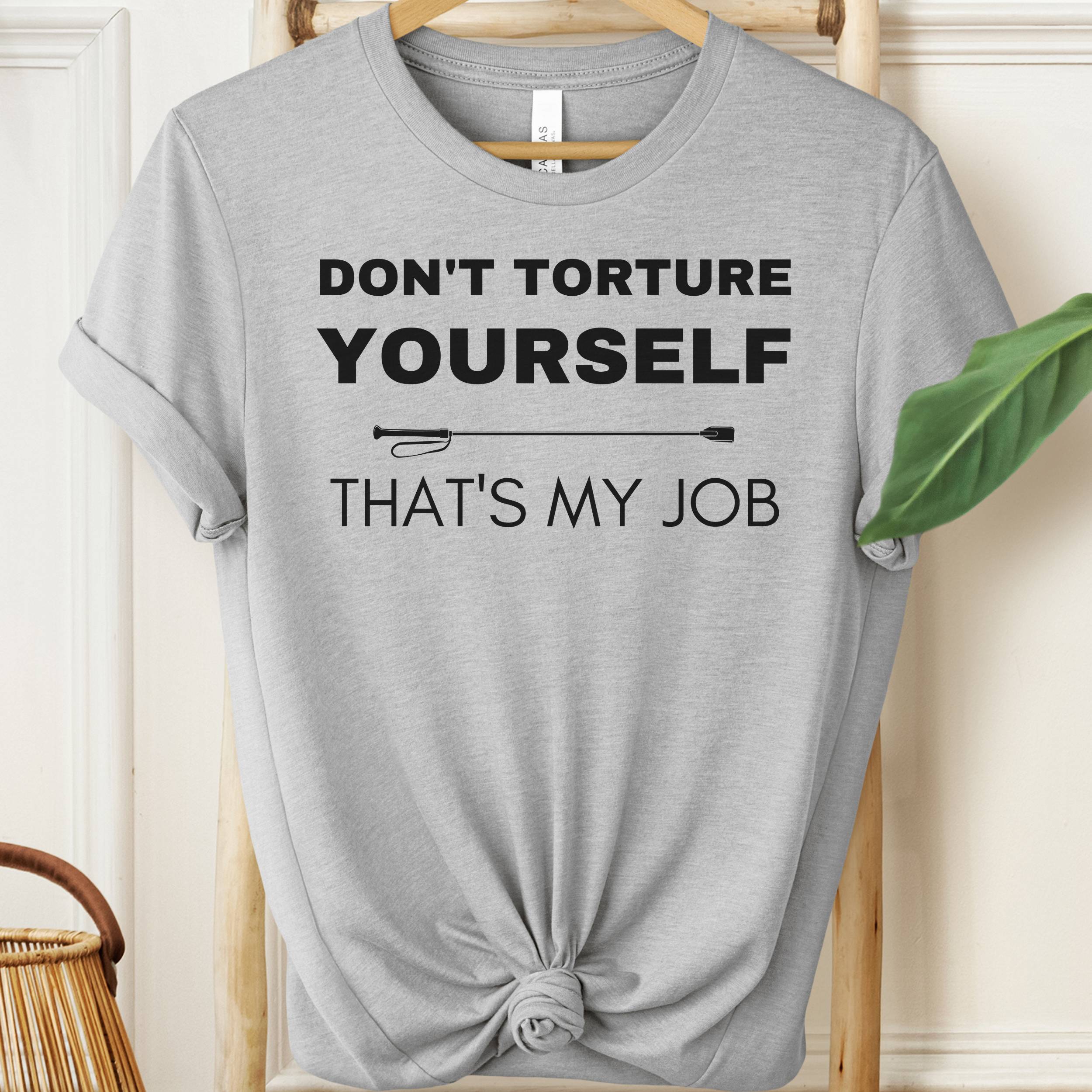 Gray t-shirt with text 'Don't torture yourself, that's my job' on a hanger.