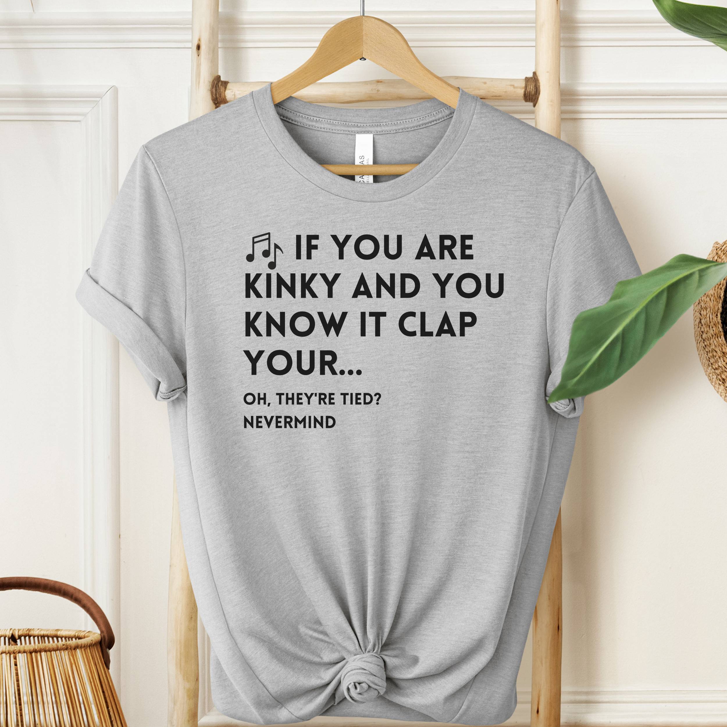 Gray t-shirt with humorous text design on a hanger against a neutral background
