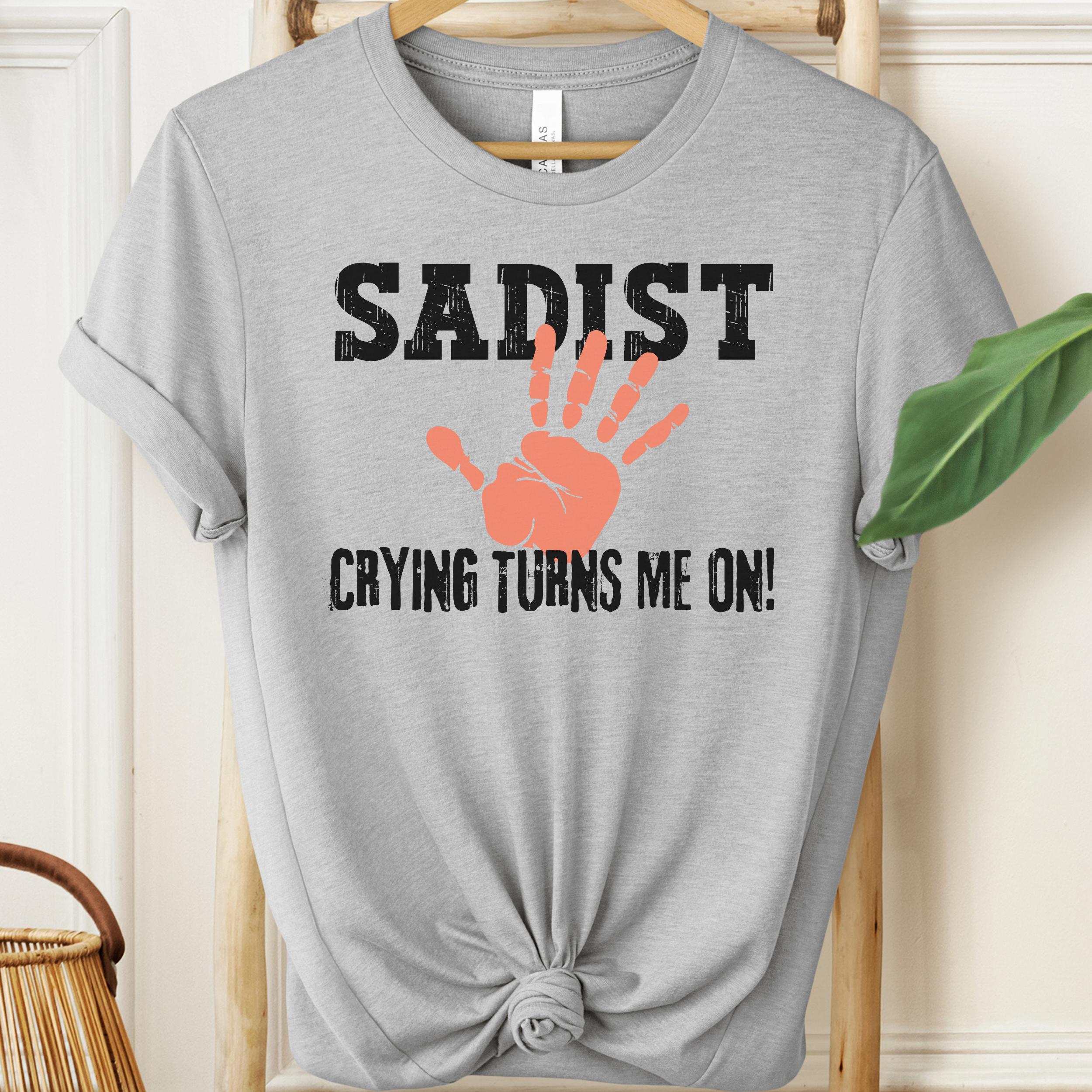 Athletic Heather t-shirt with 'SADIST CRYING TURNS ME ON!' text and hand print graphic on a hanger.
