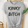 Gray t-shirt with 'KINKY BITCH' text on a hanger.