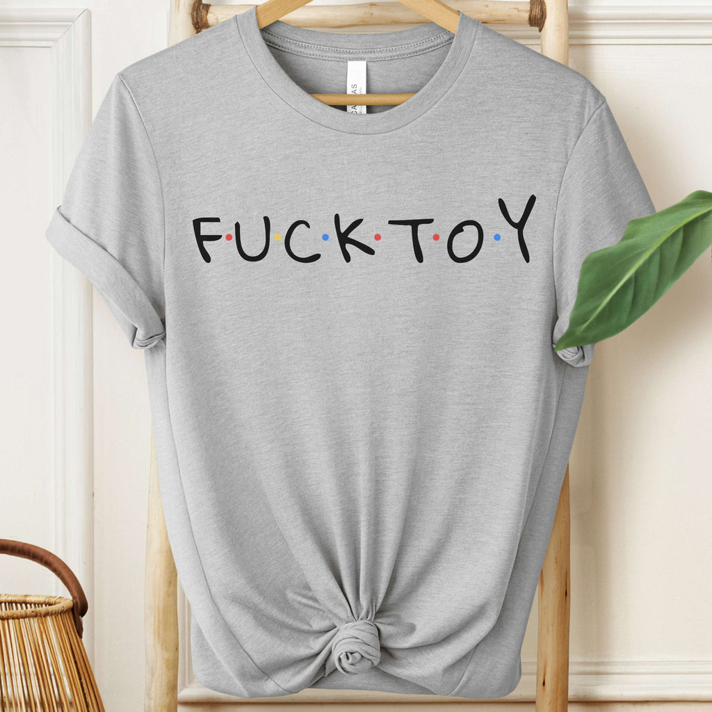 Gray t-shirt with 'FUCKTOY' text on a hanger against a neutral background
