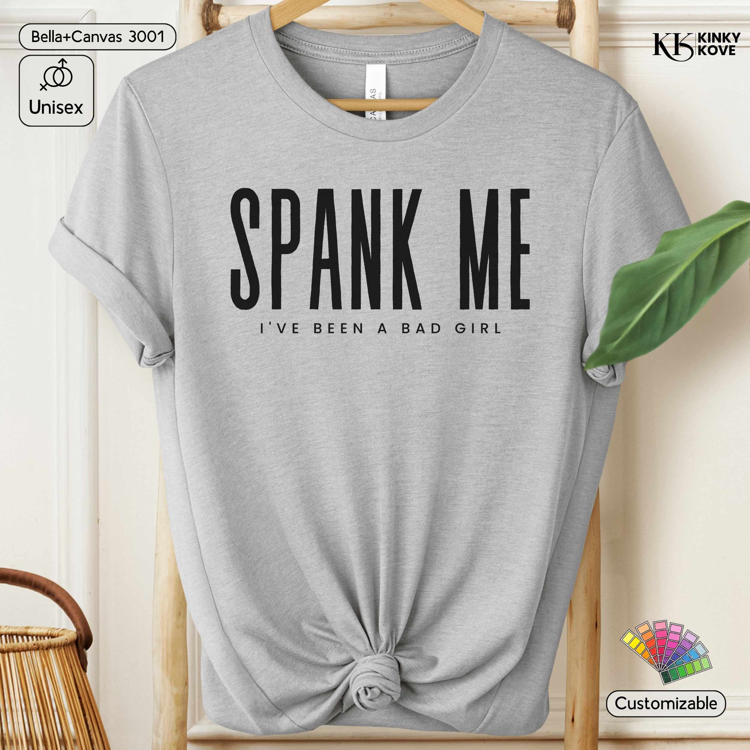 Gray t-shirt with 'SPANK ME I'VE BEEN A BAD GIRL' text on a hanger.