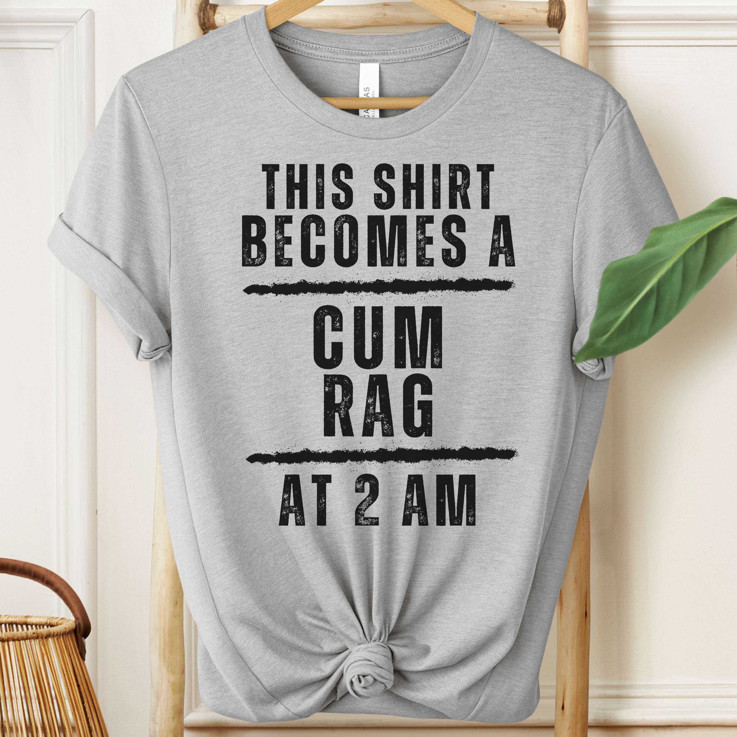 Gray t-shirt with humorous text on a hanger against a neutral background