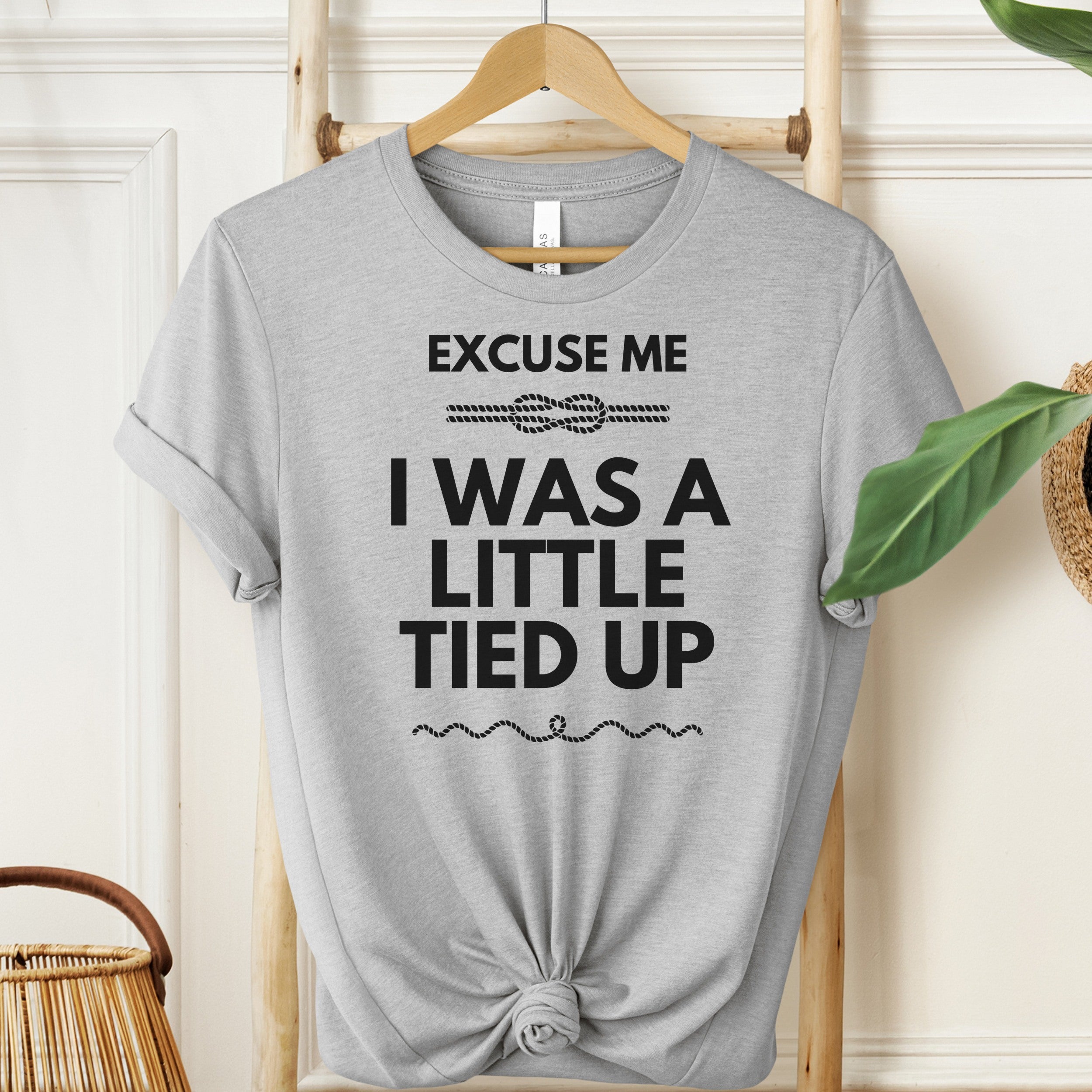 Gray t-shirt with humorous text design on a hanger against a neutral background