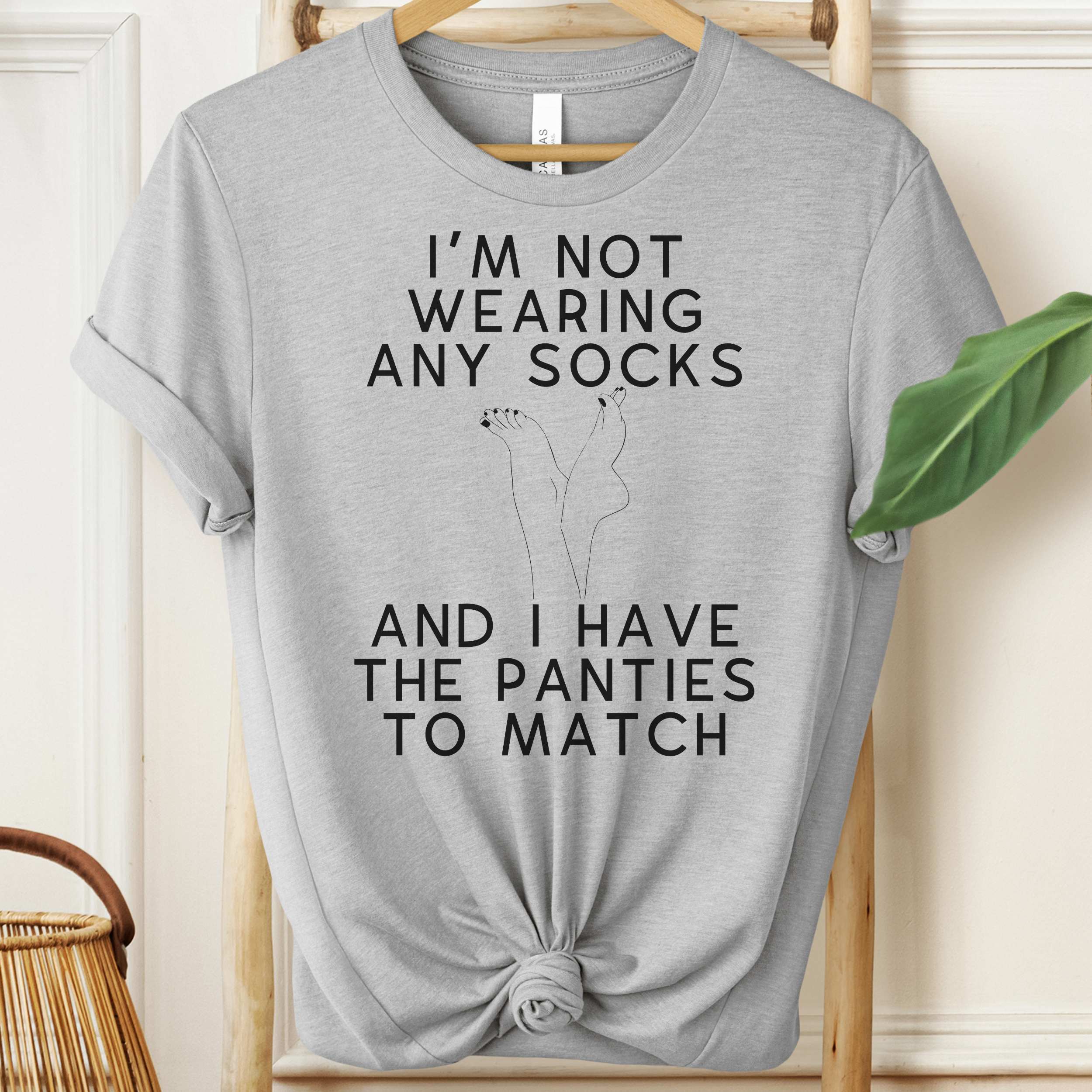 Gray t-shirt with humorous text design on a hanger.