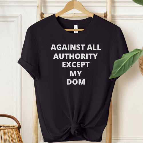 Black t-shirt with white text 'AGAINST ALL AUTHORITY EXCEPT MY DOM' on a hanger.
