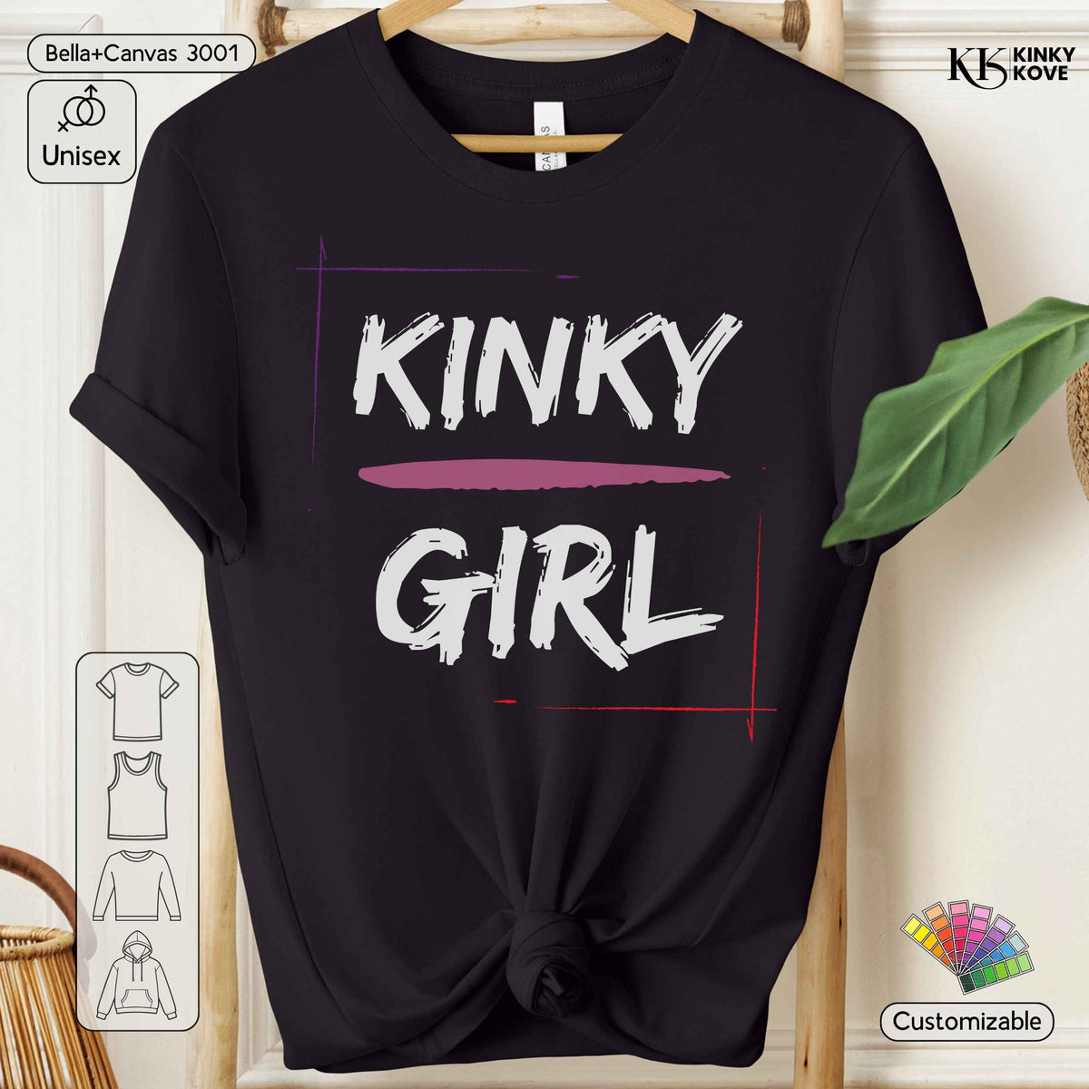 A black short-sleeve t-shirt with a graphic print reading 'KINKY GIRL' in white brush-style lettering, with a pink horizontal line under 'KINKY' and red/purple framing lines. The shirt is displayed on a wooden hanger against a light beige background with decorative props including a green leaf, a basket edge, and informational overlays.