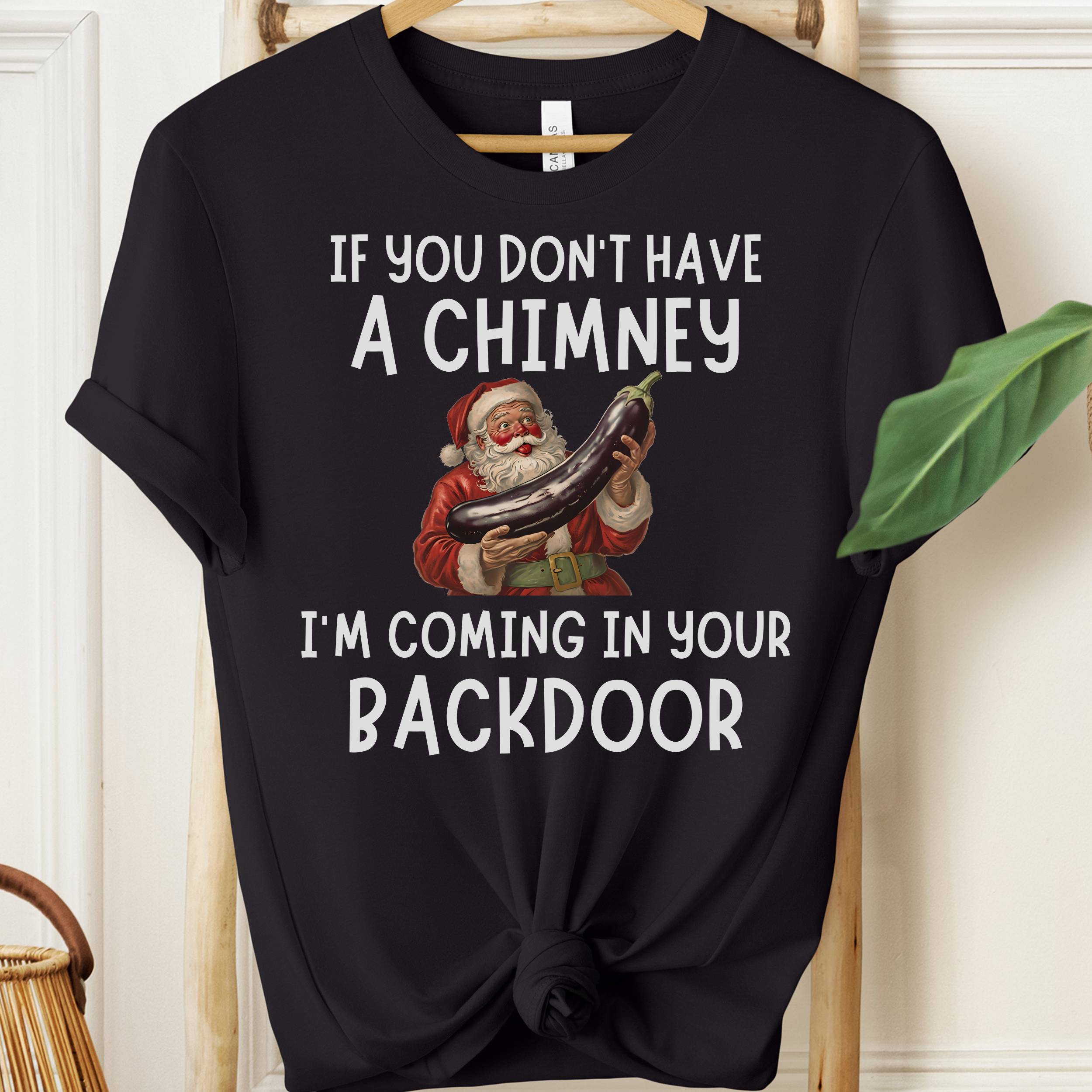 Black t-shirt with Santa Claus graphic and humorous text on a hanger.