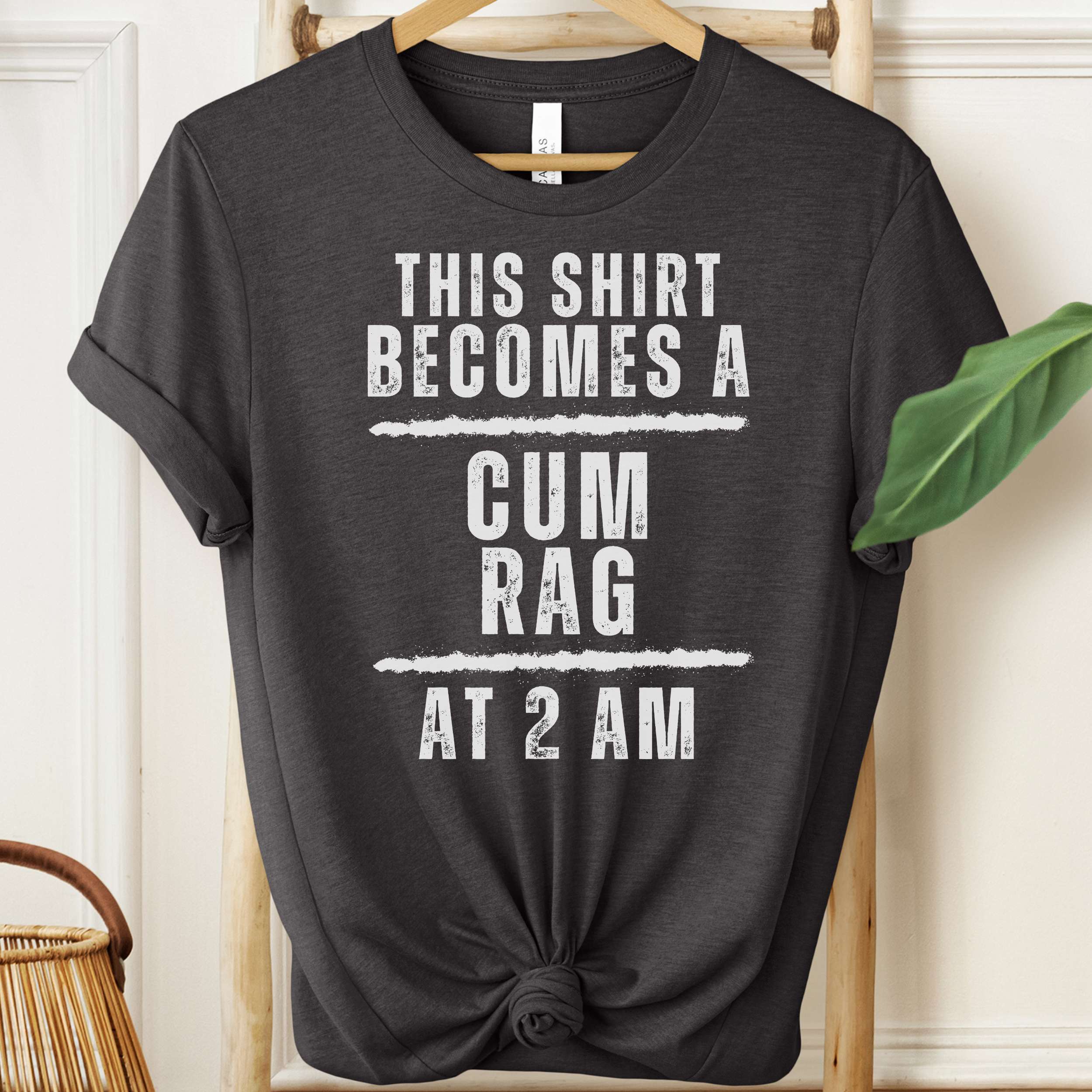 Black t-shirt with white text on a hanger against a neutral background
