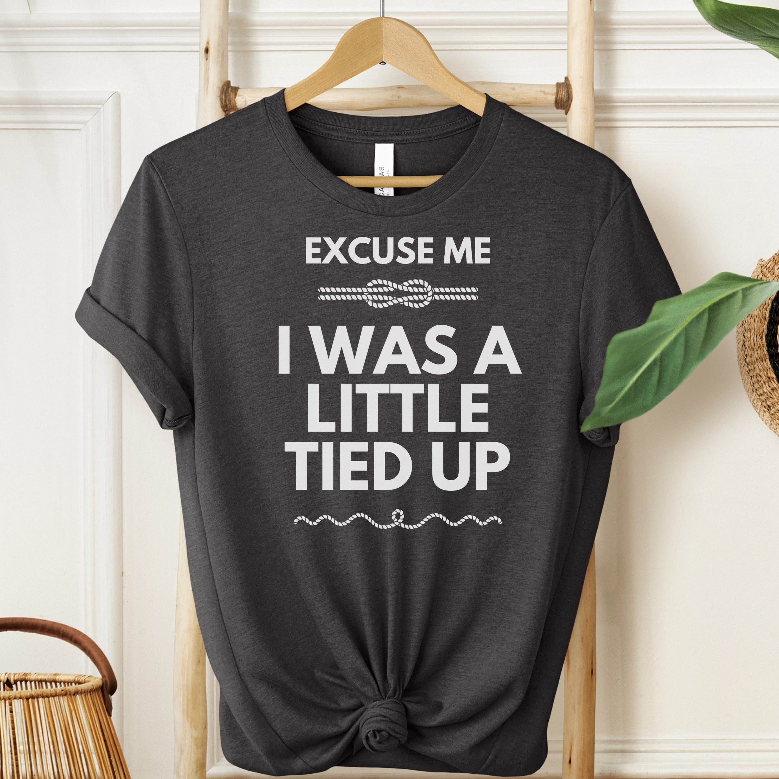 Black t-shirt with white text on a hanger against a neutral background