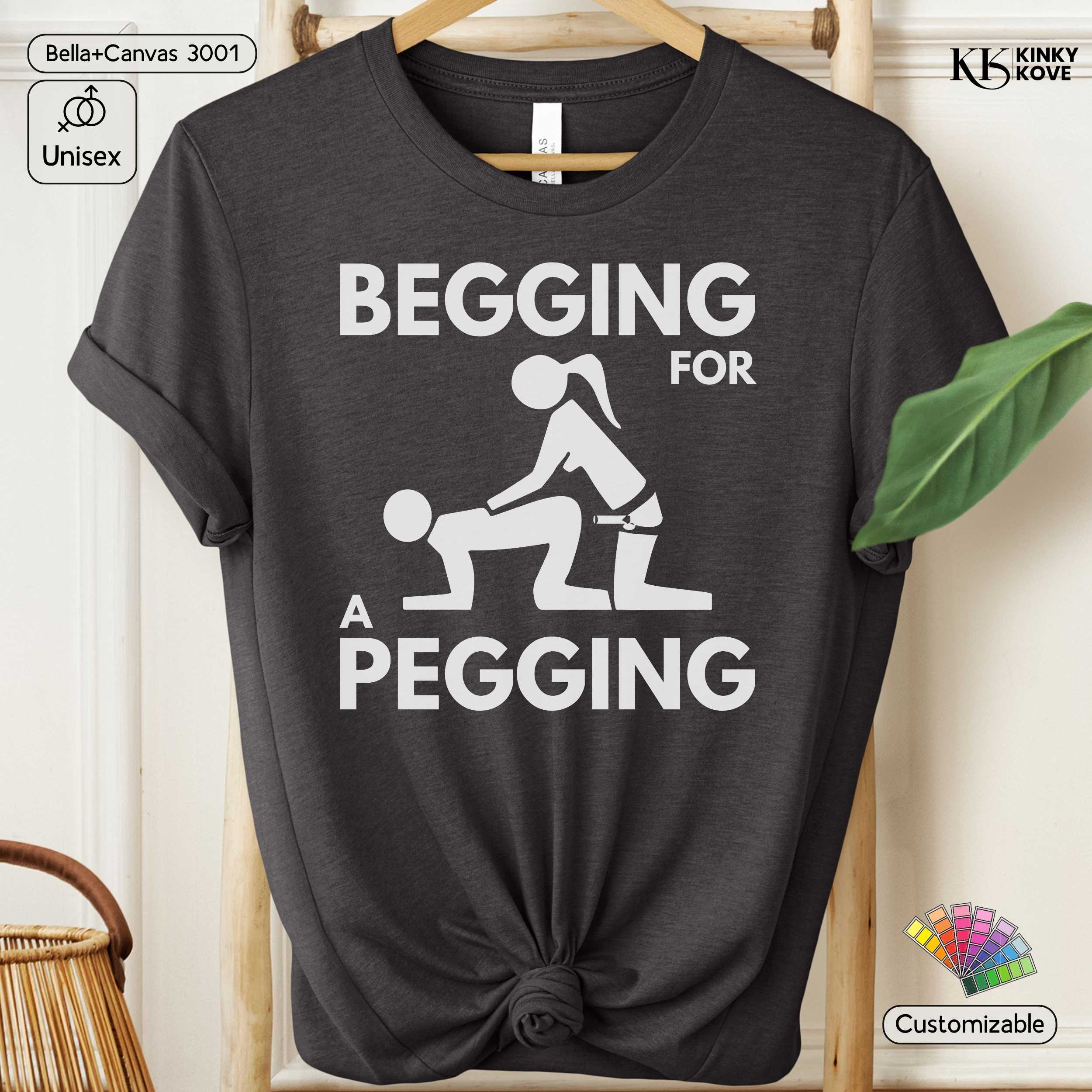 Black t-shirt with graphic design and text 'Begging for a Pegging' on a hanger.