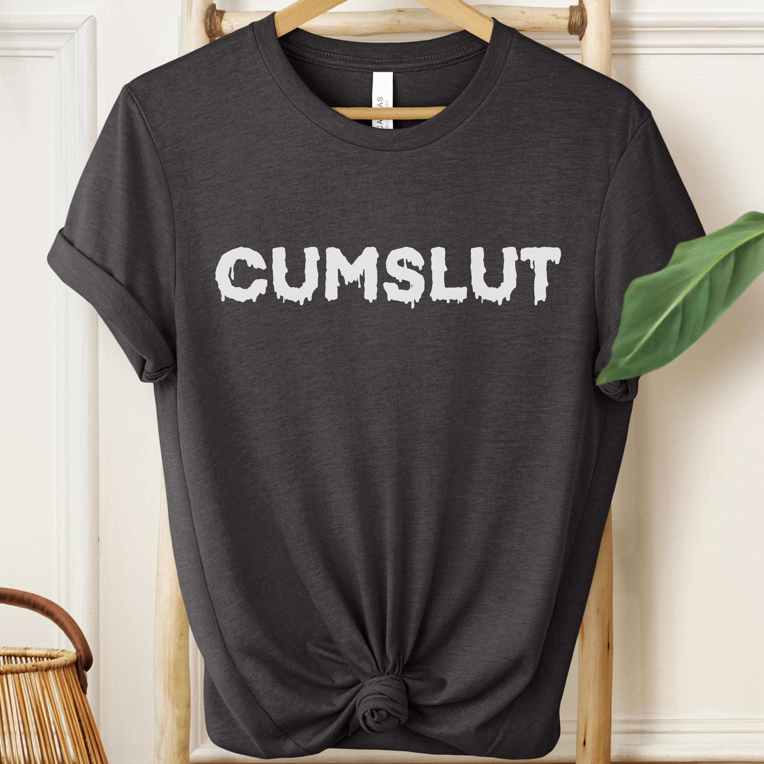 Black t-shirt with 'CUMSLUT' printed in white on a hanger.