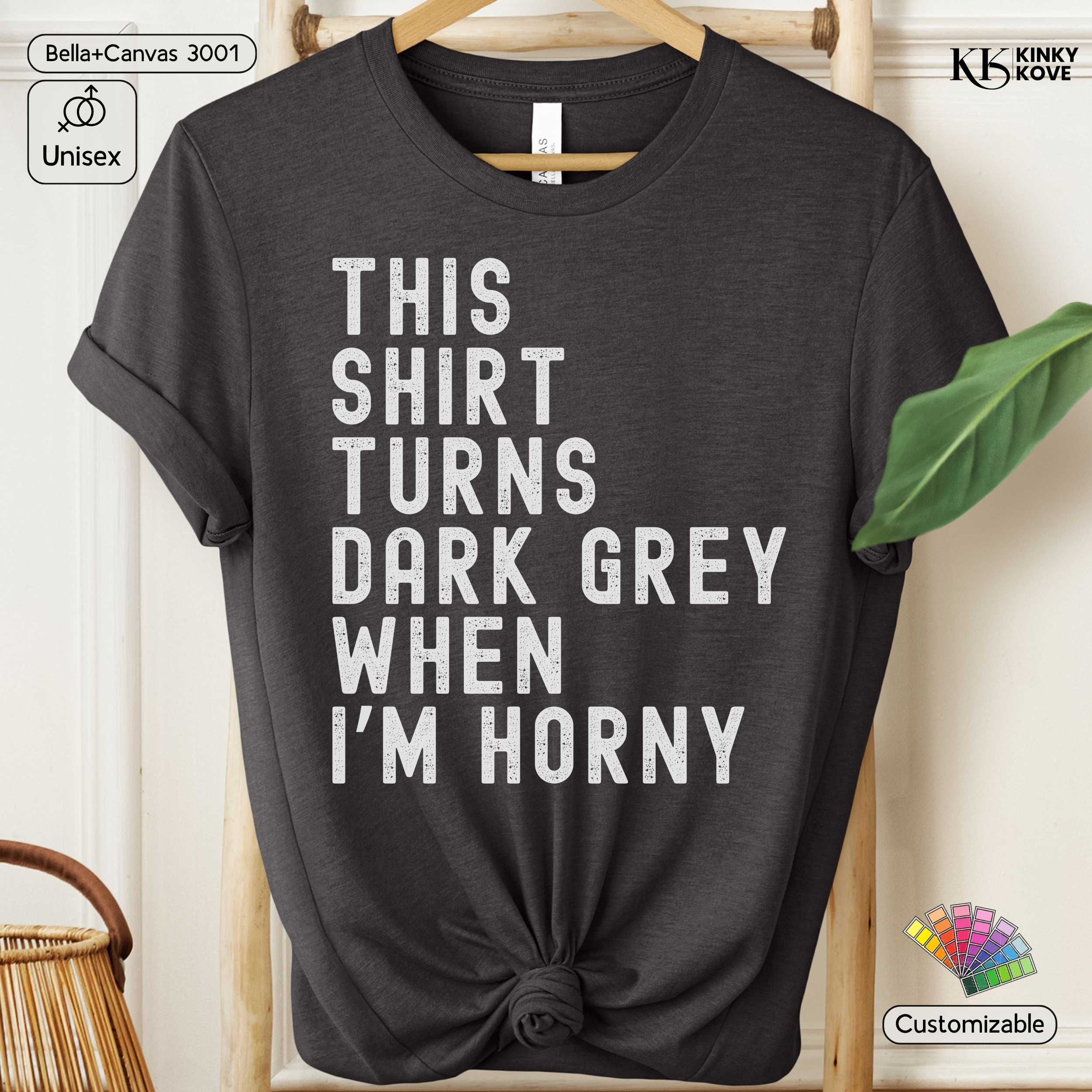 Dark grey t-shirt with humorous text on a hanger against a neutral background
