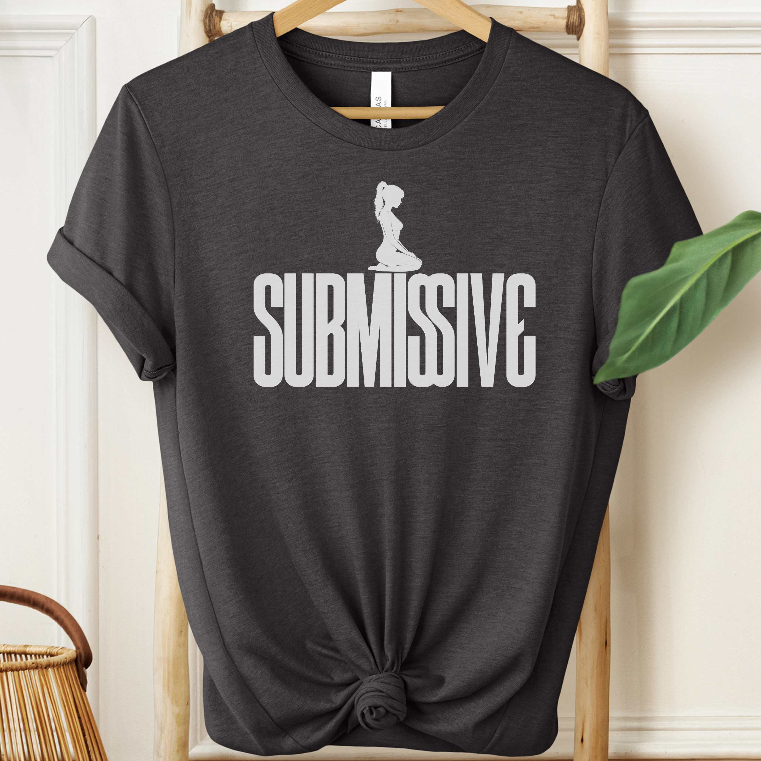 Black t-shirt with 'SUBMISSIVE' text and white graphic on a wooden hanger.