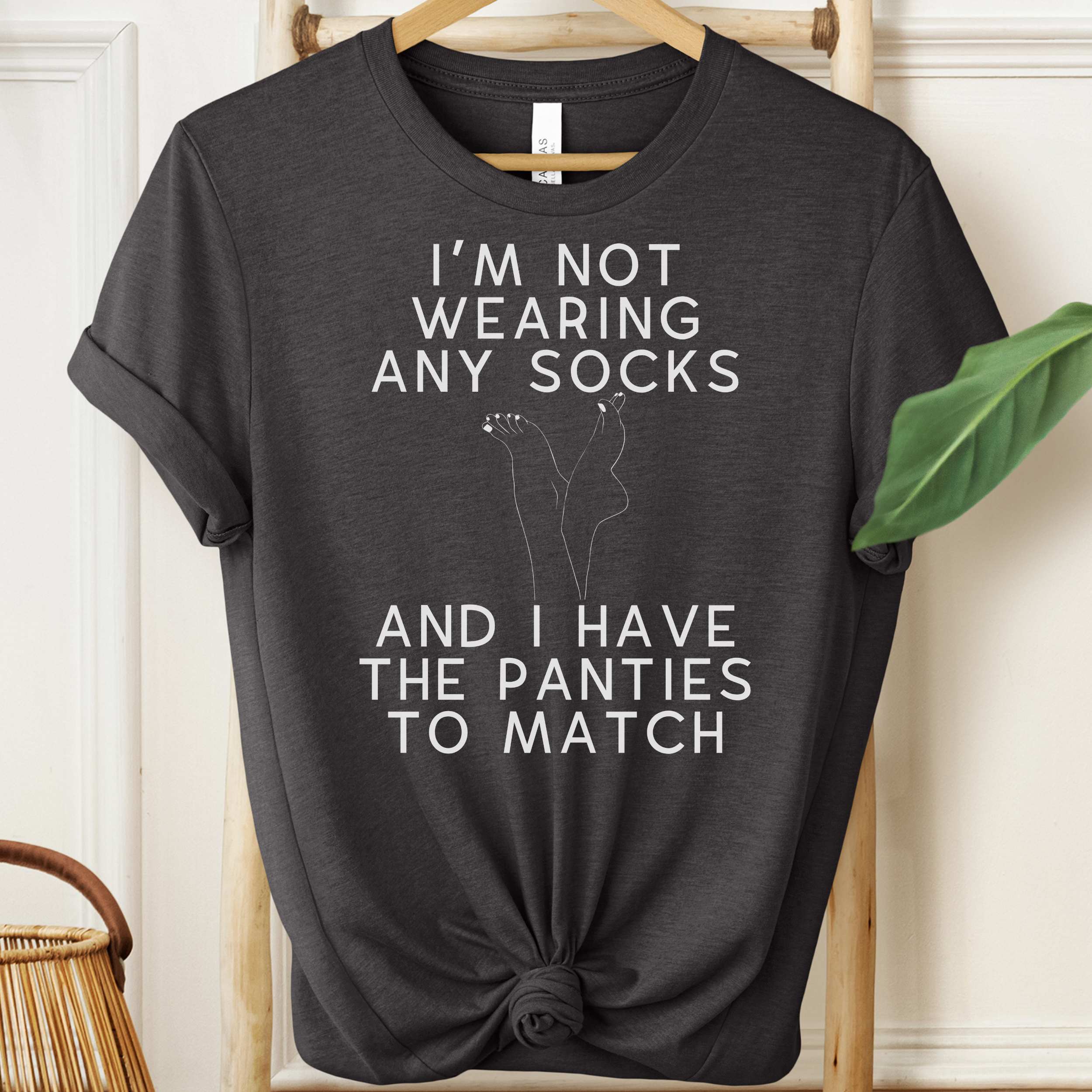 Black t-shirt with humorous text and graphic on a hanger against a neutral background