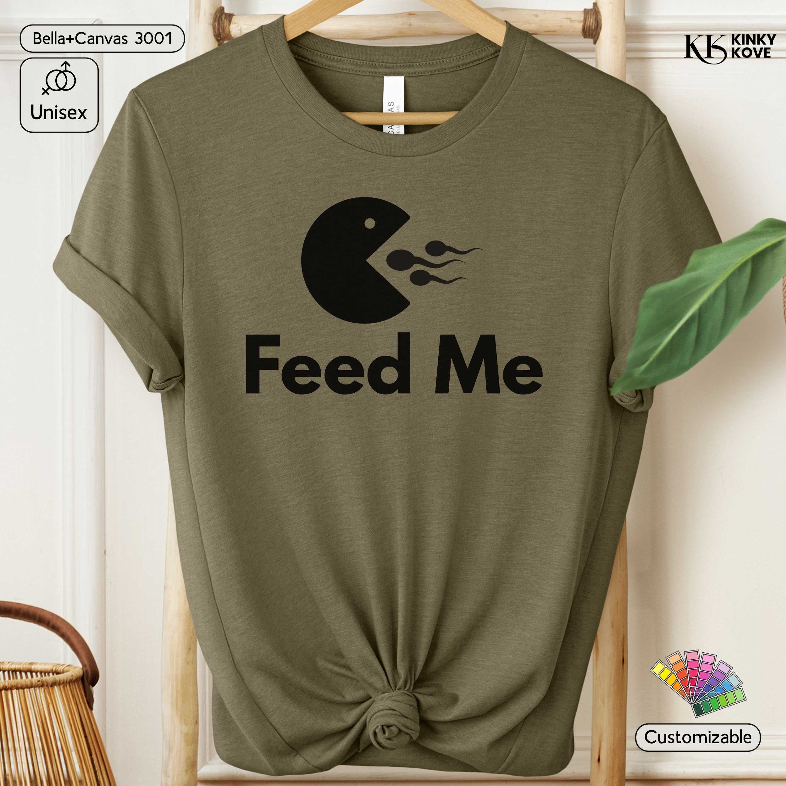 Green t-shirt with 'Feed Me' graphic design on a hanger against a white background.