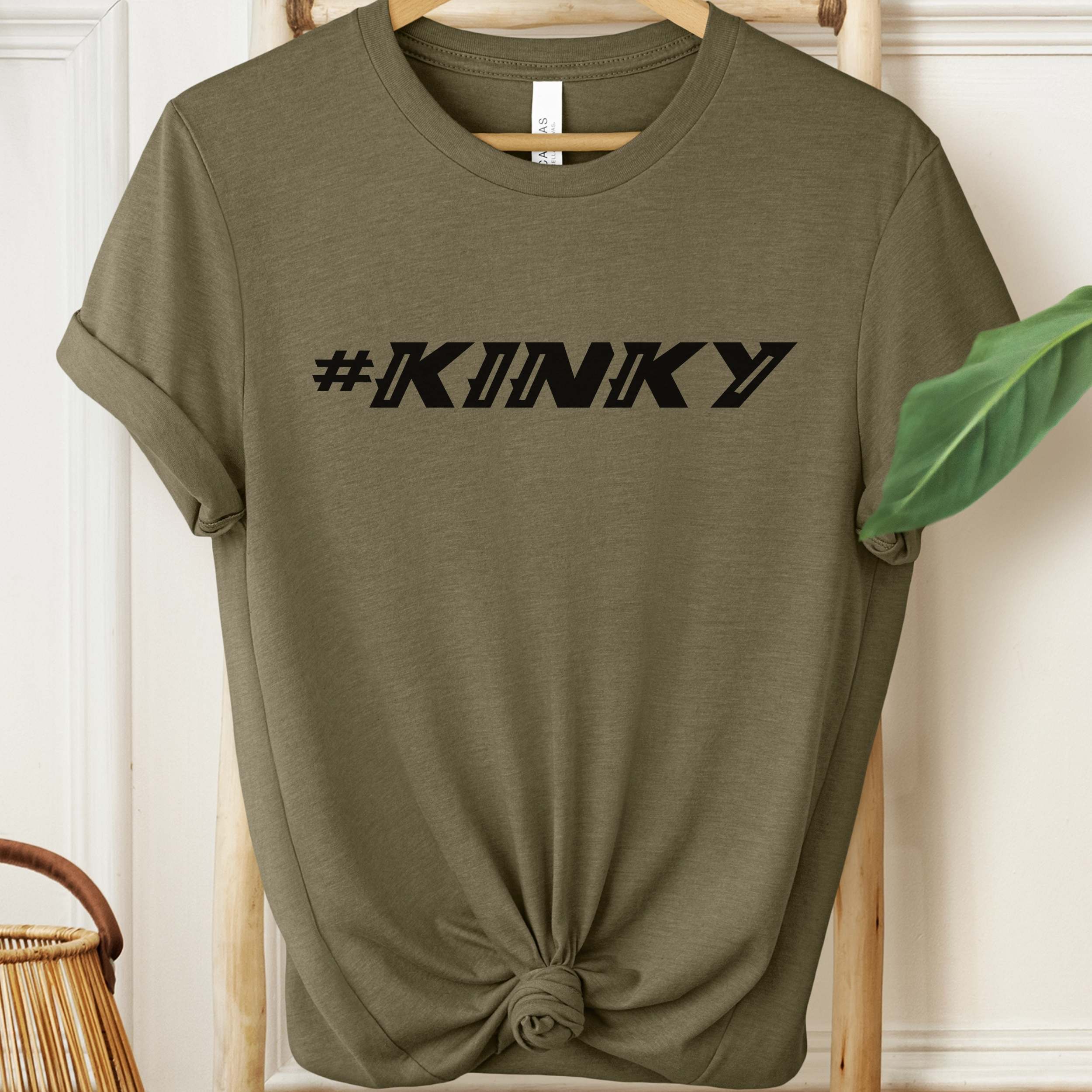 Olive green t-shirt with '#KINKY' text on a hanger.