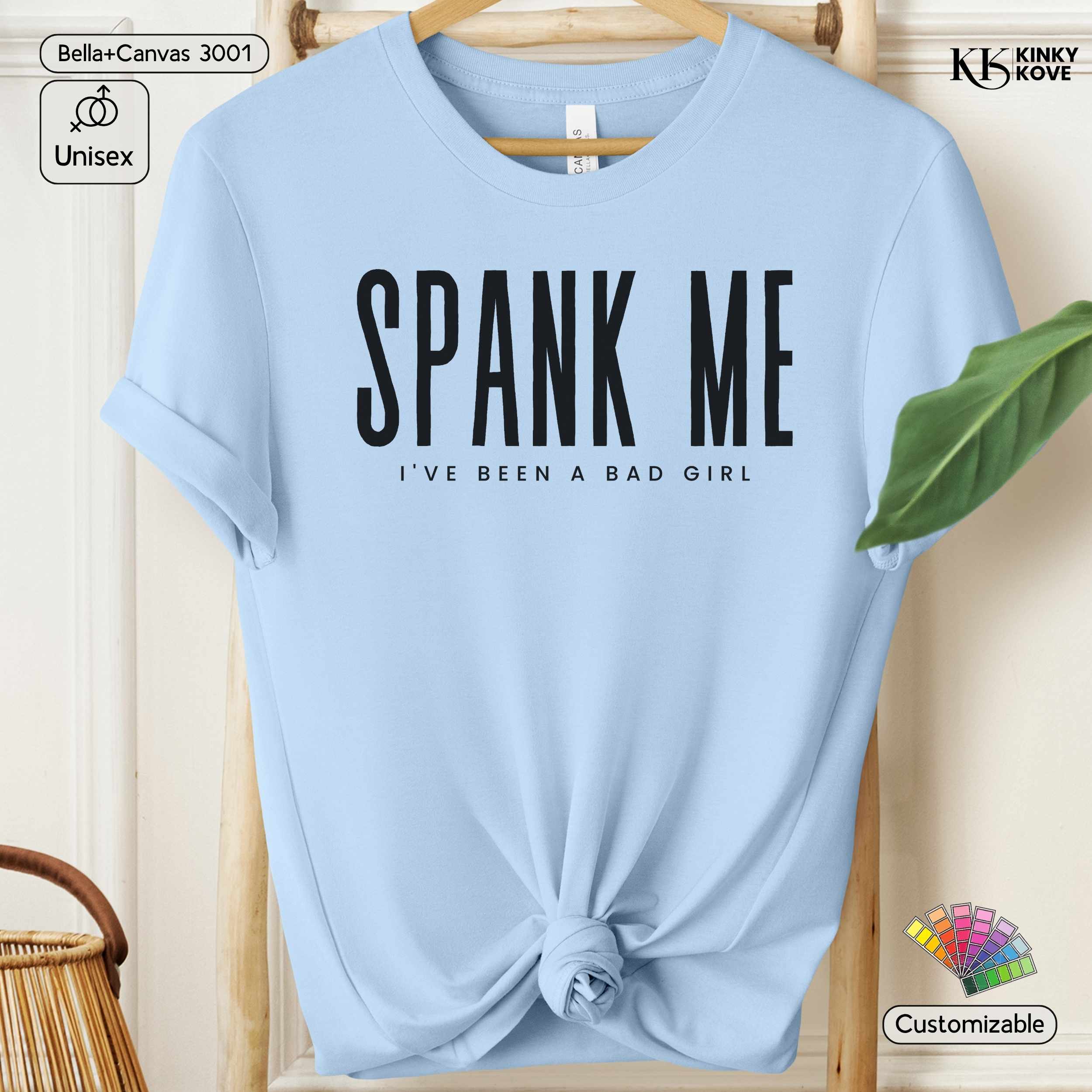 Light blue t-shirt with 'SPANK ME I've Been a Bad Girl' text on a wooden hanger.