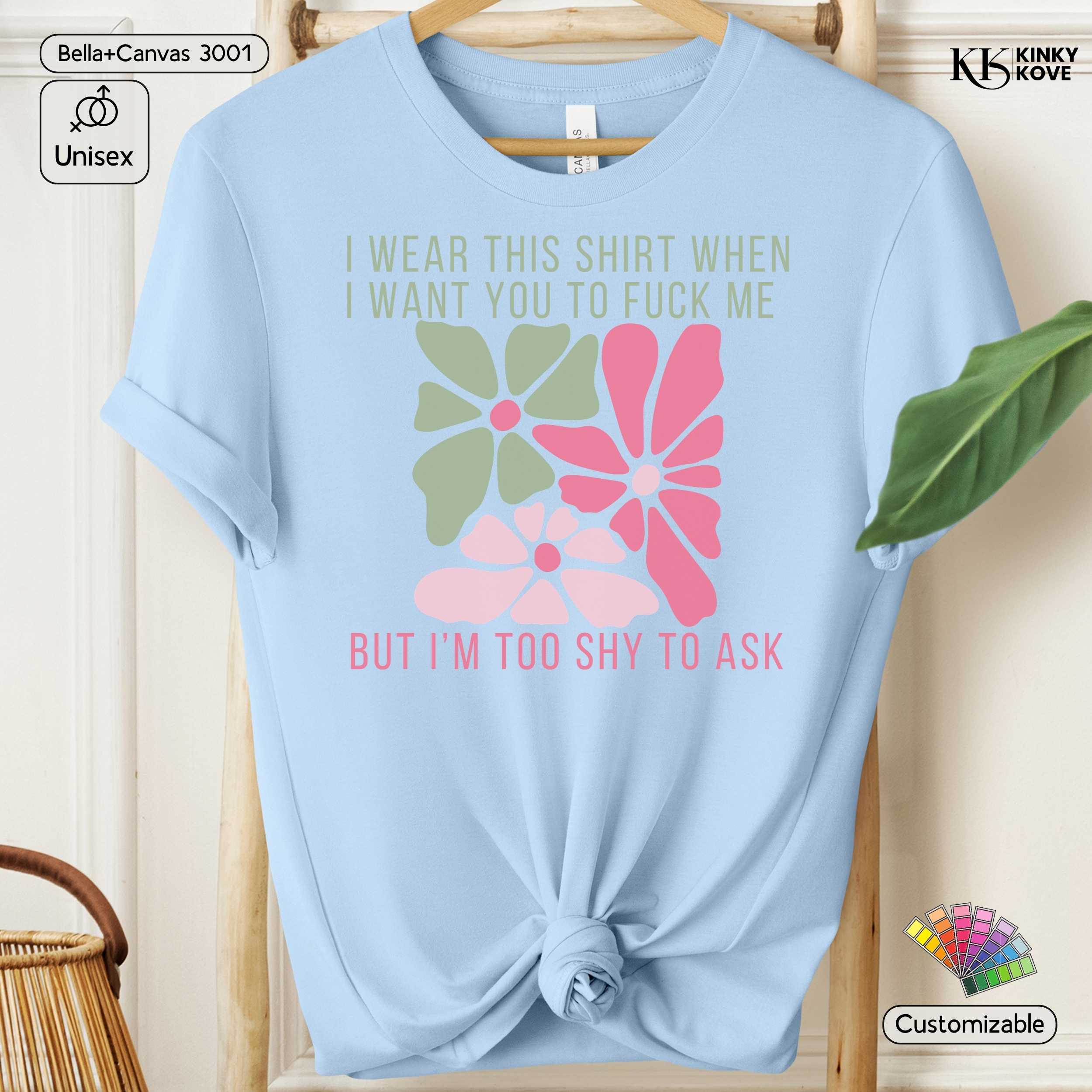 Light blue t-shirt with floral design and text on a wooden hanger.