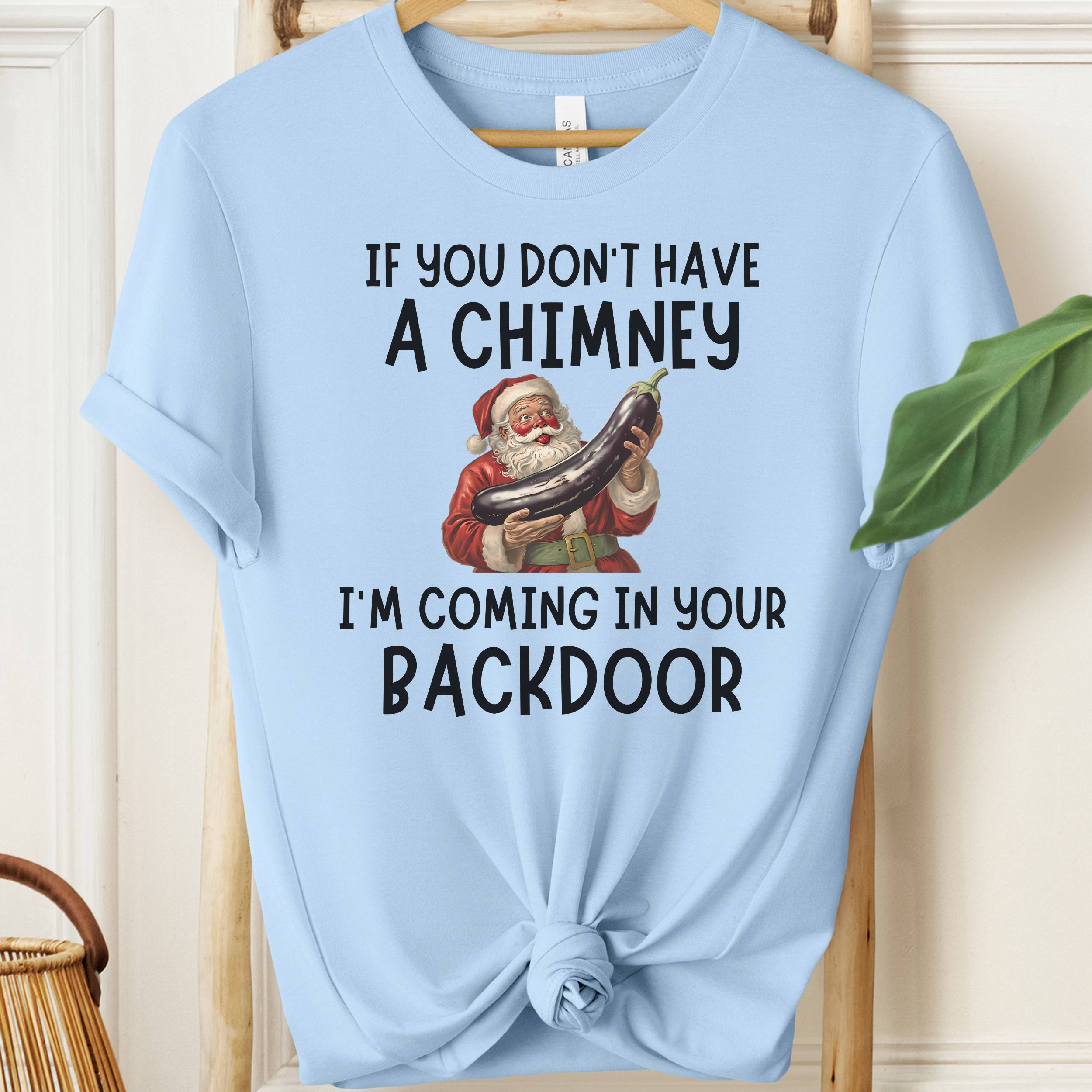 Light blue t-shirt with Santa Claus graphic and humorous text on a wooden surface.