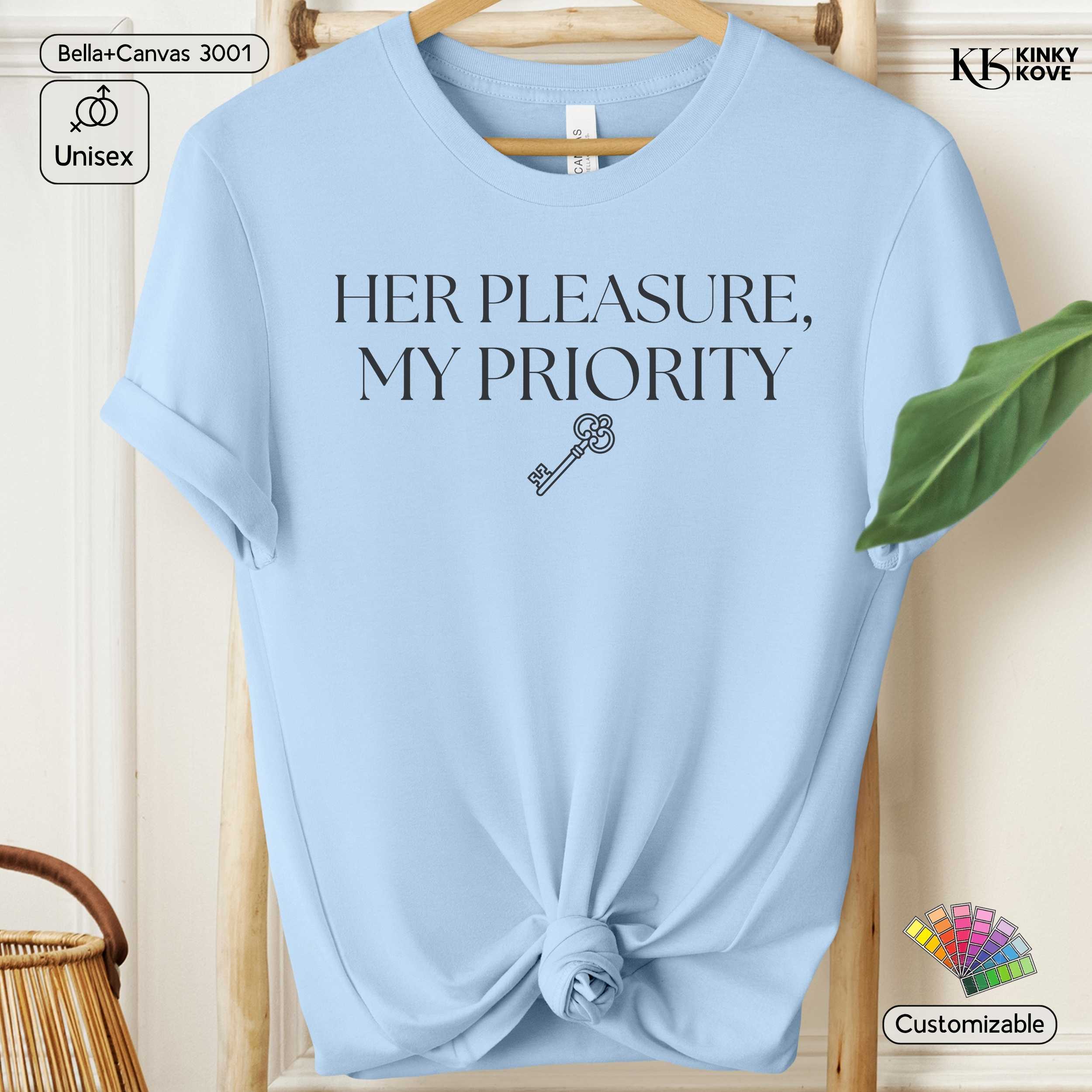 Light blue t-shirt with 'HER PLEASURE, MY PRIORITY' text and key graphic on a wooden hanger.