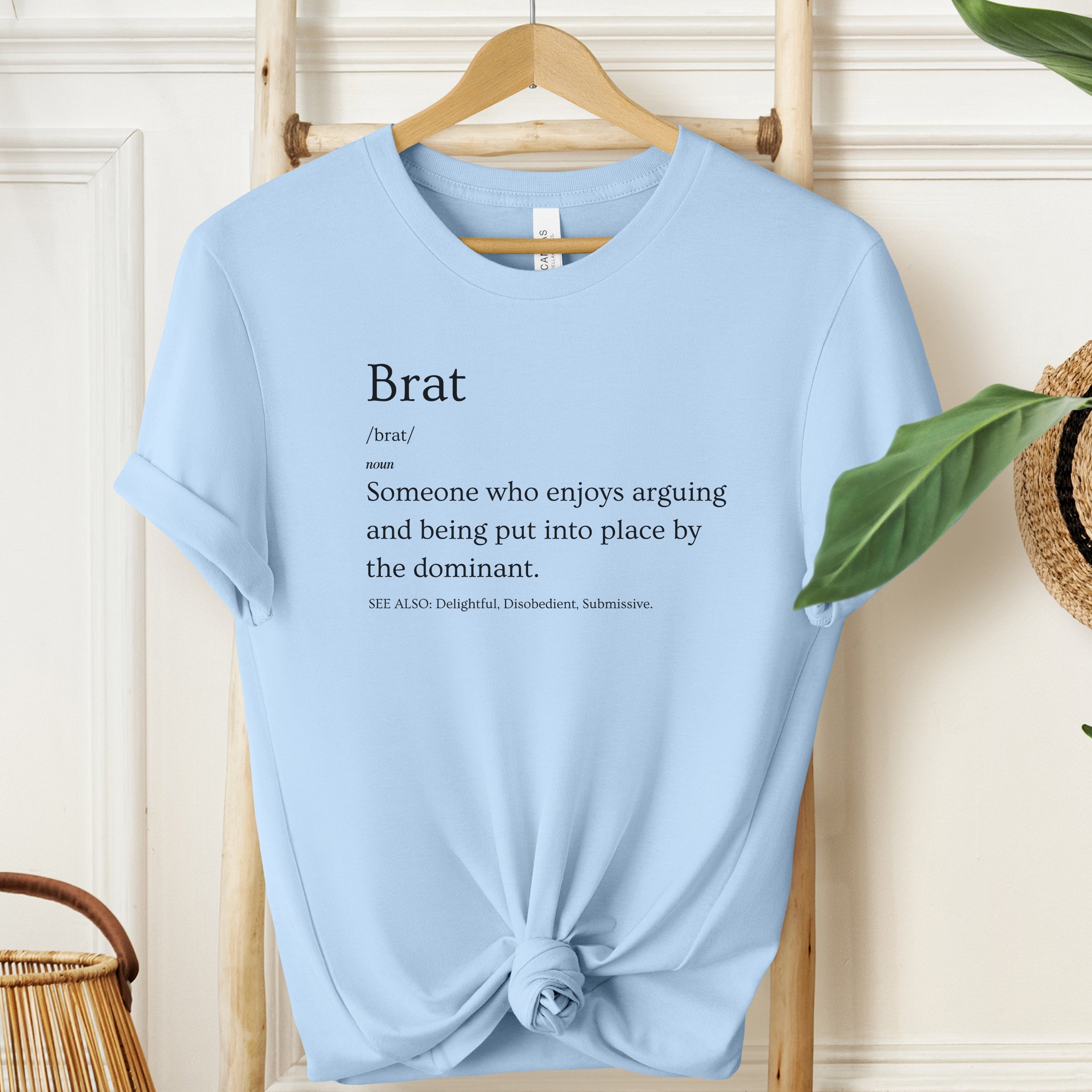 Light blue t-shirt with text on a hanger against a neutral background