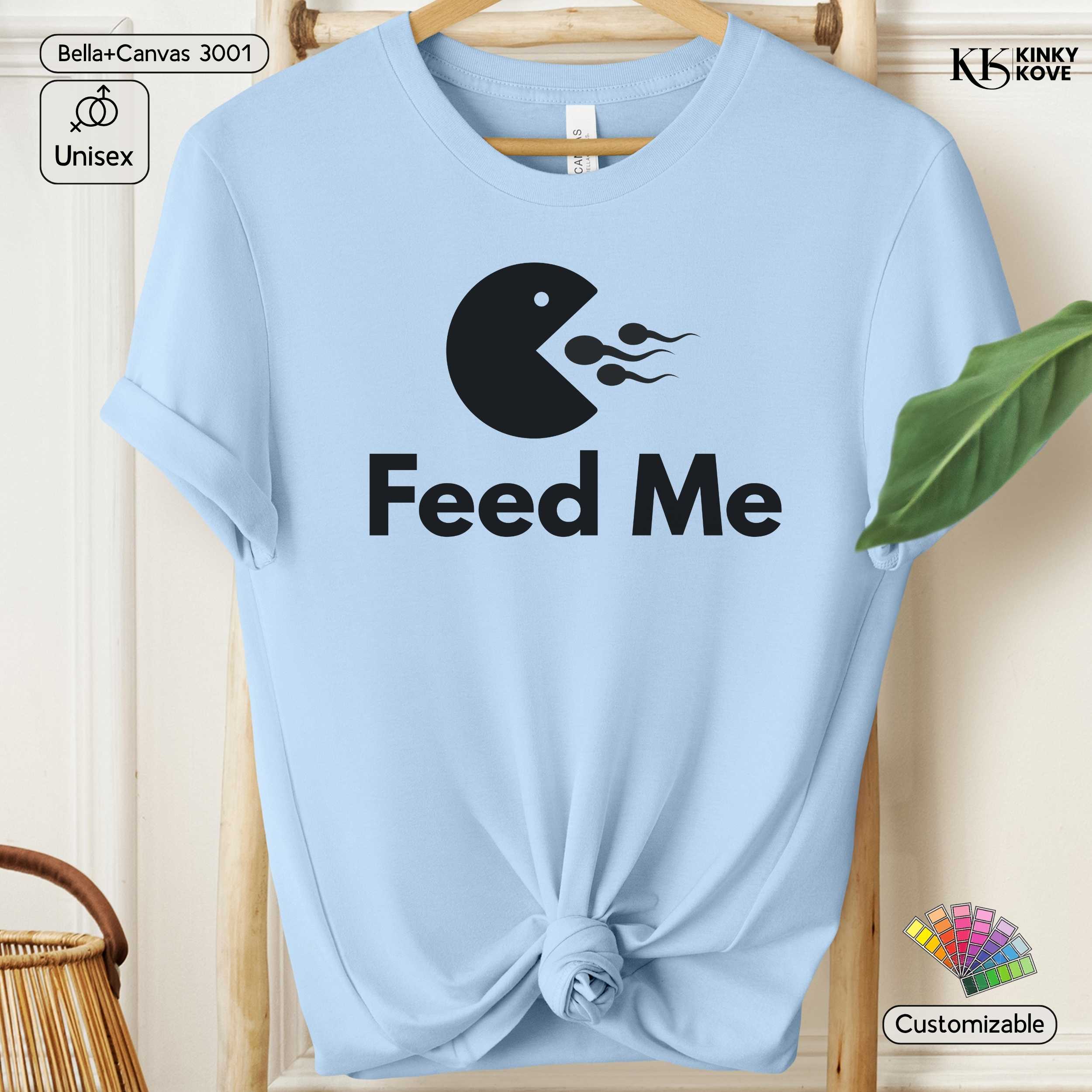 Light blue t-shirt with black graphic and 'Feed Me' text on a wooden hanger.