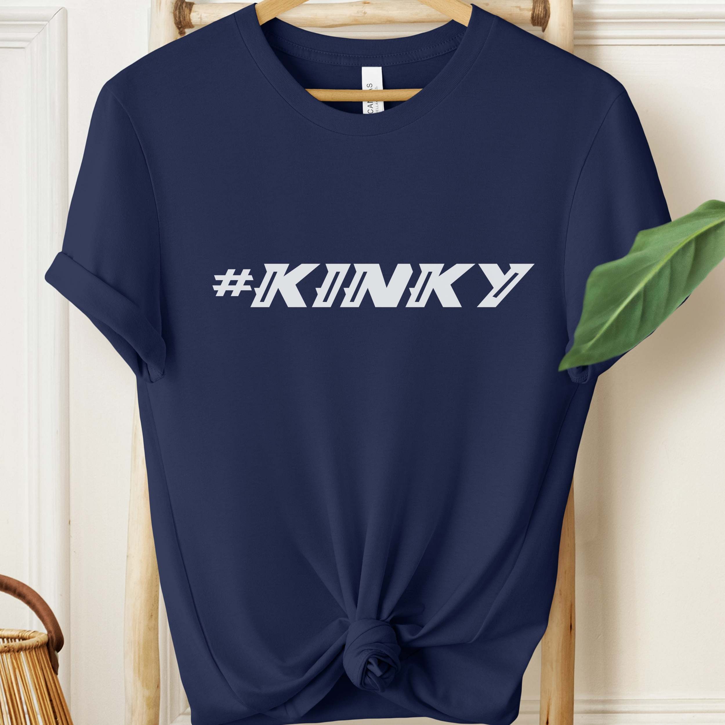 Navy blue t-shirt with '#KINKY' text on a wooden hanger.