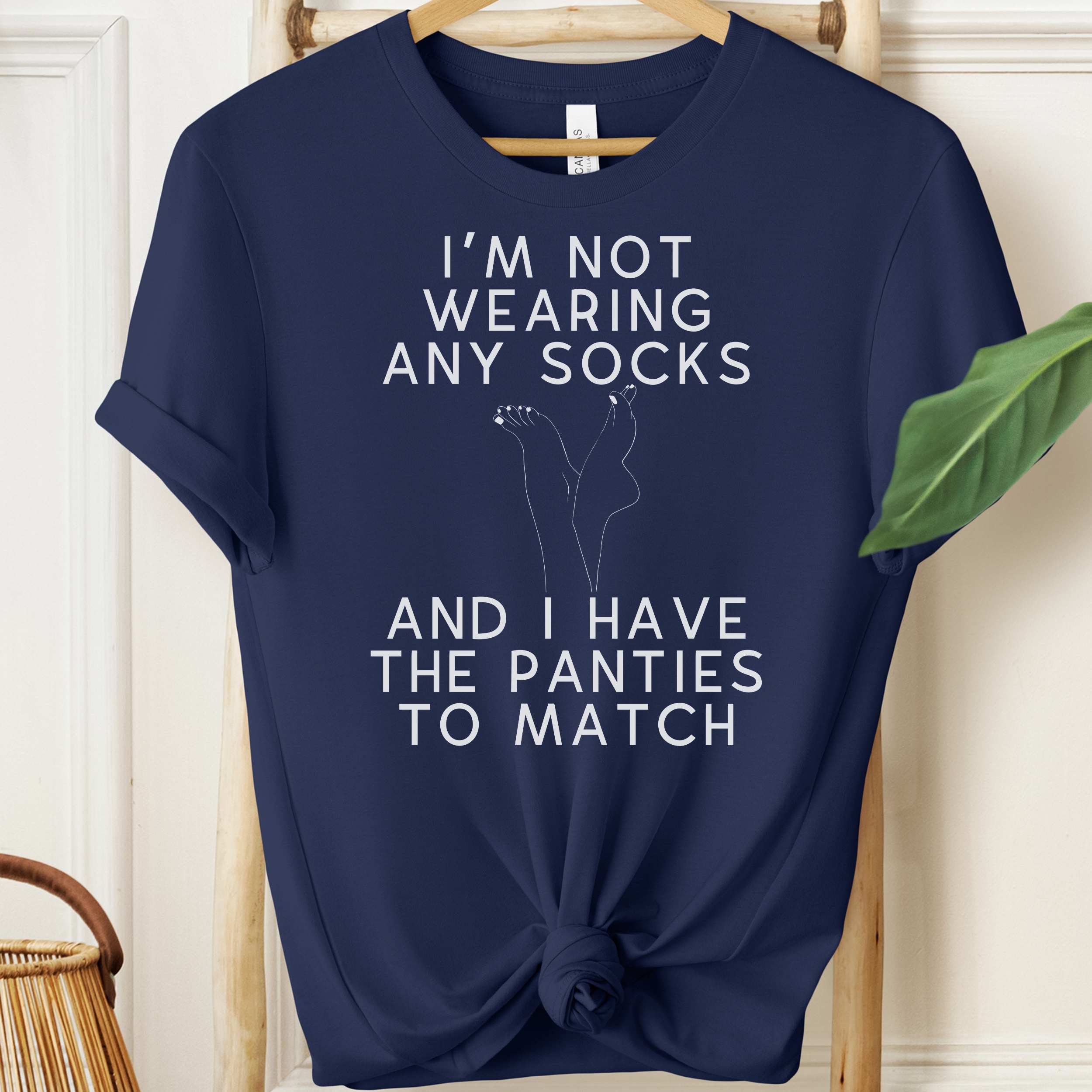 Navy blue t-shirt with humorous text design on a wooden hanger.