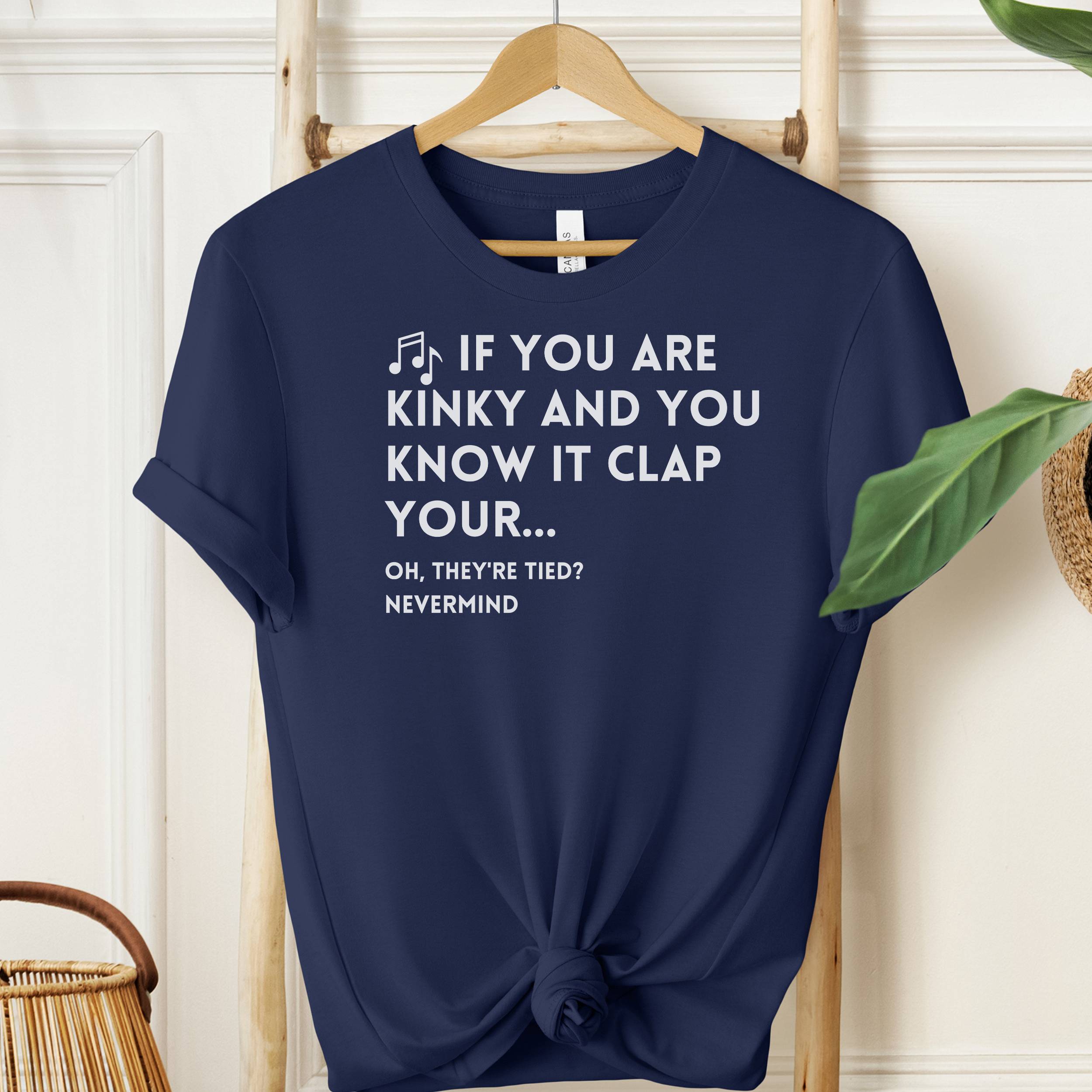 Navy blue t-shirt with humorous text design on a wooden hanger against a white wall.