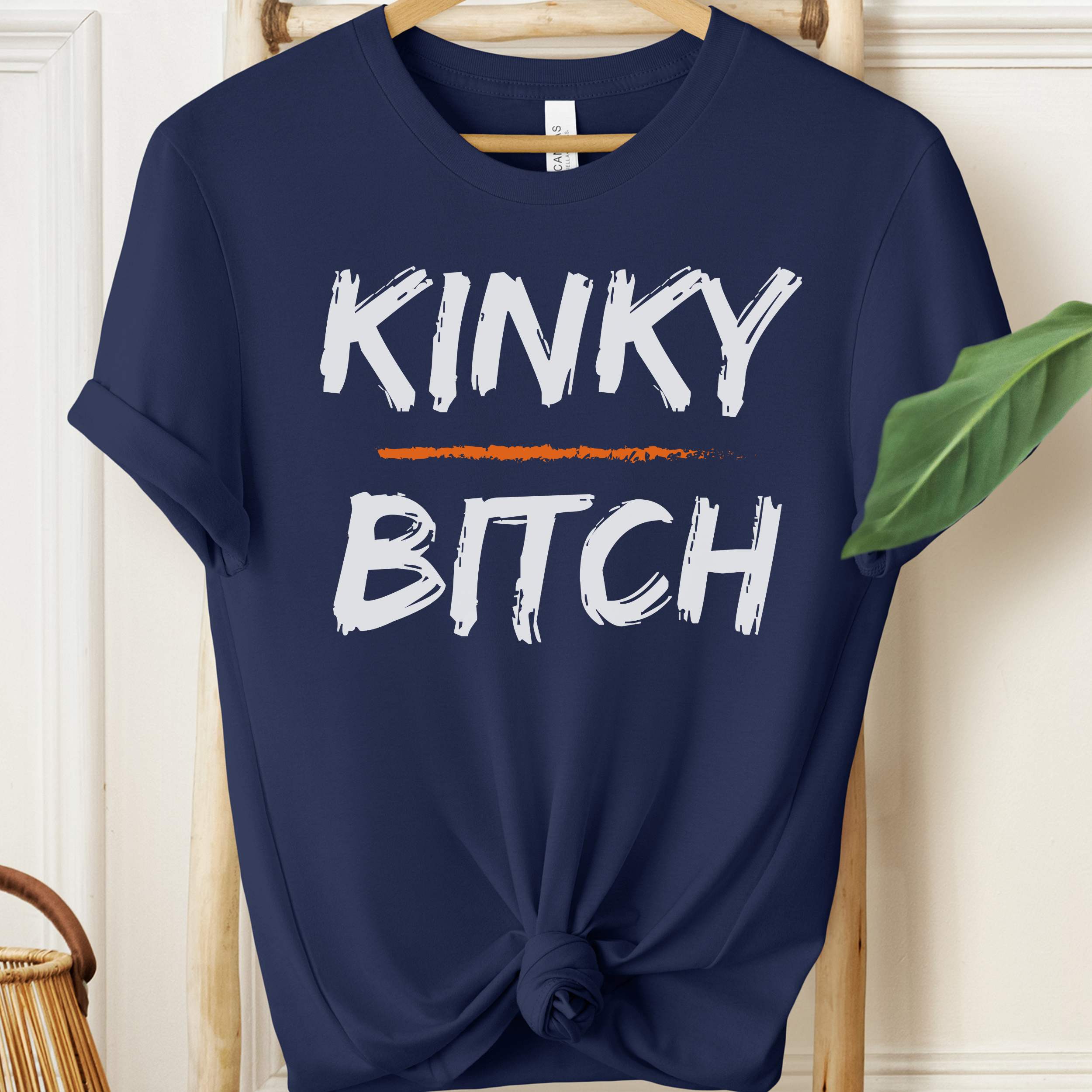 Navy blue t-shirt with 'KINKY BITCH' text on a hanger.