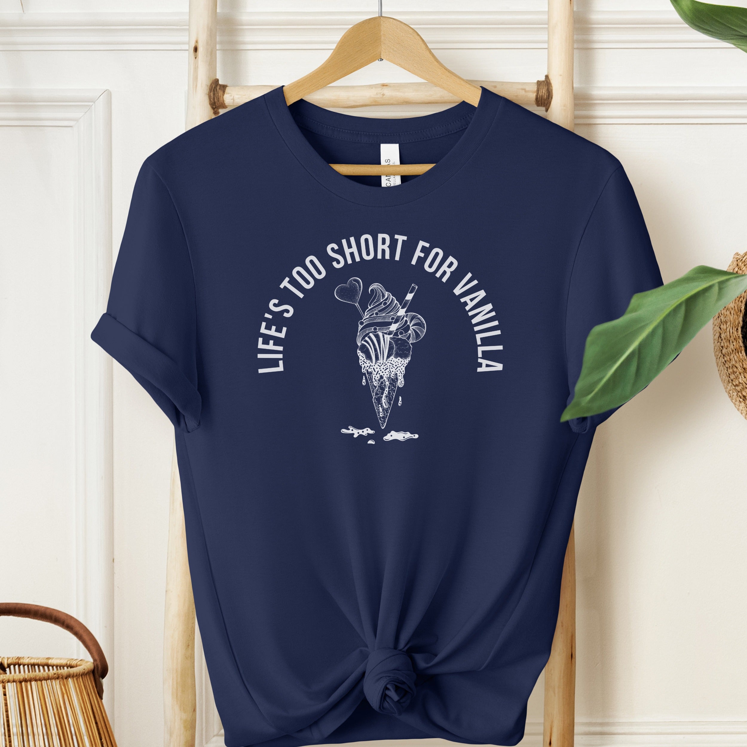 Navy blue t-shirt with ice cream graphic and text on a hanger against a white wall.