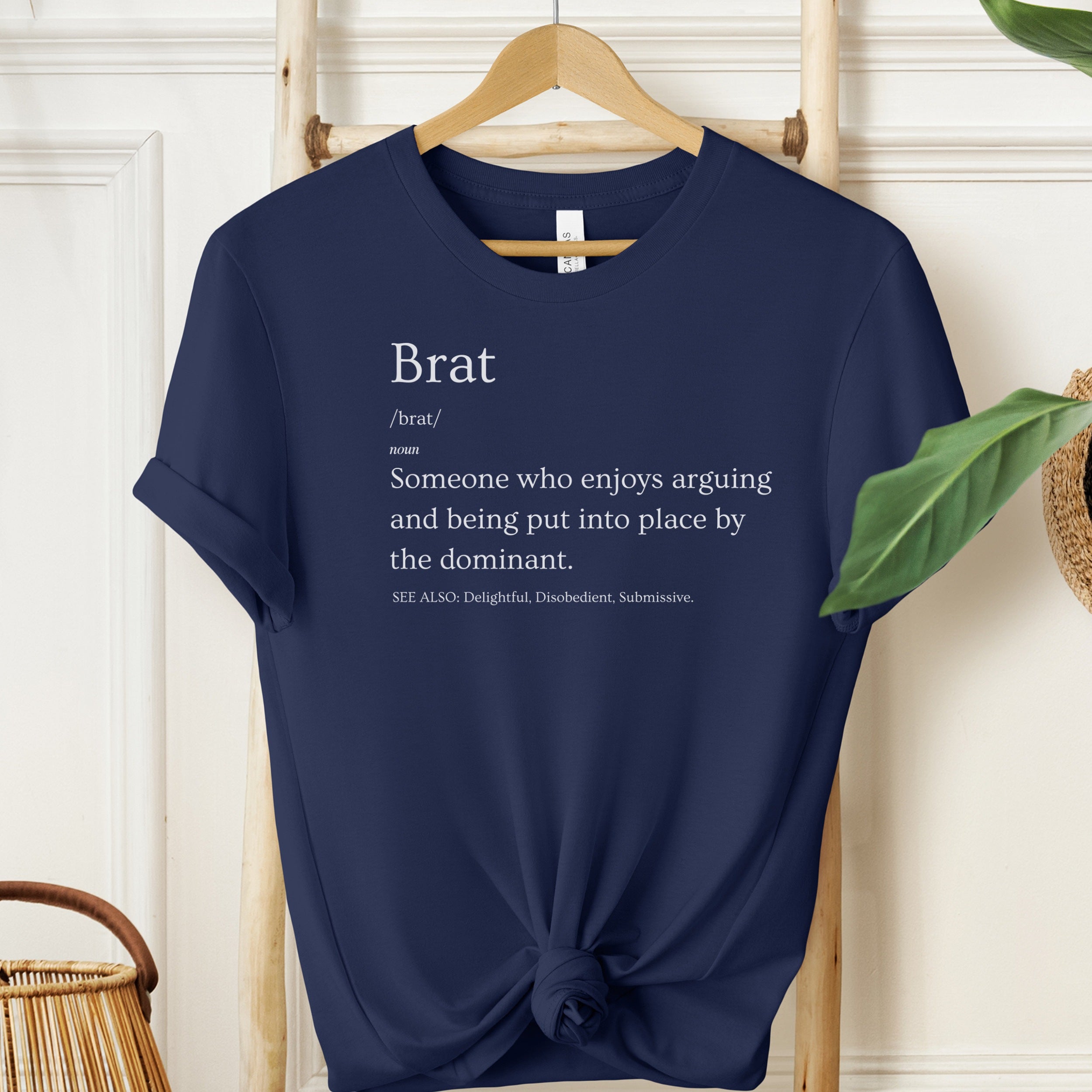 Navy blue t-shirt with text on a hanger against a white wall.