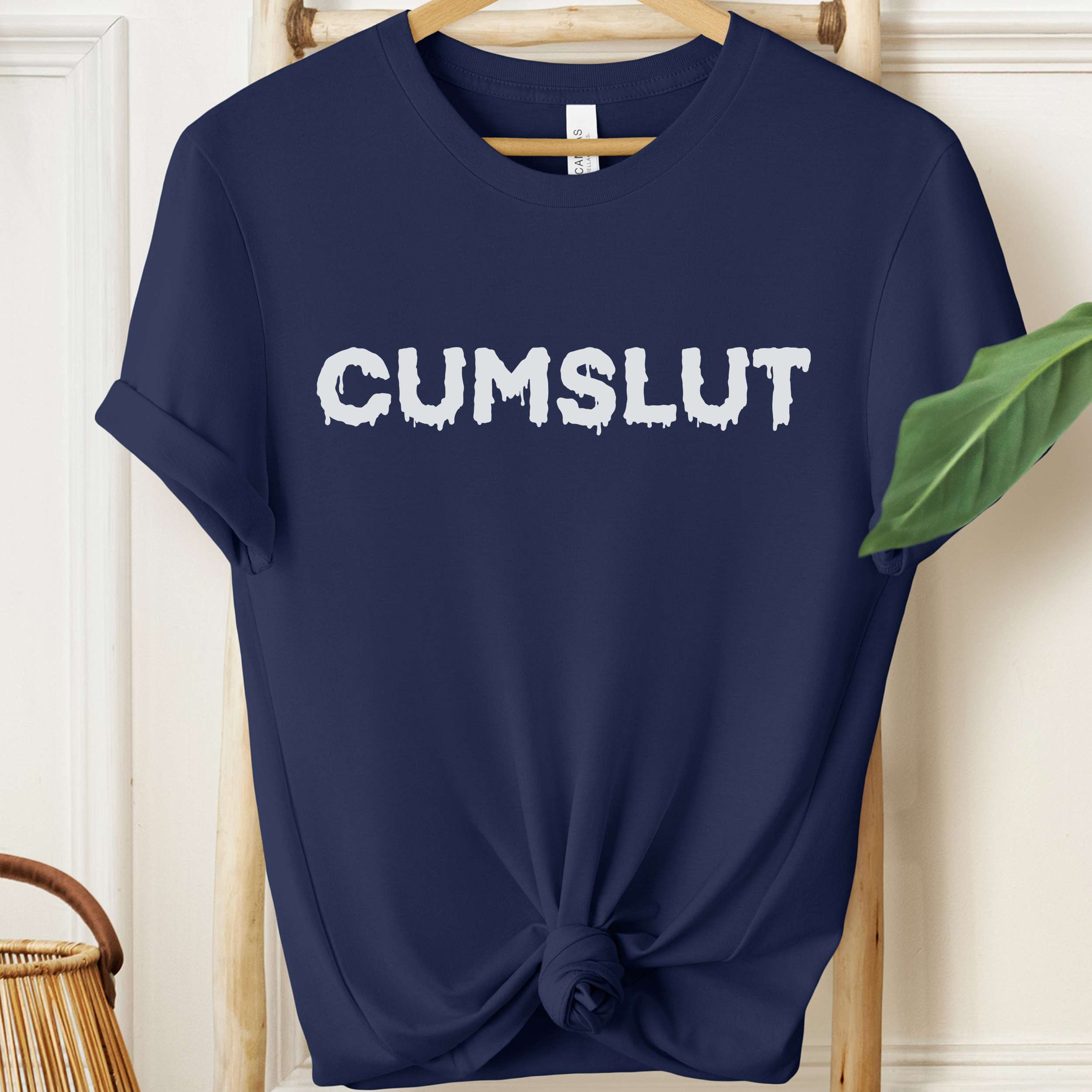 Navy blue t-shirt with 'CUMSLUT' printed in white on a hanger.