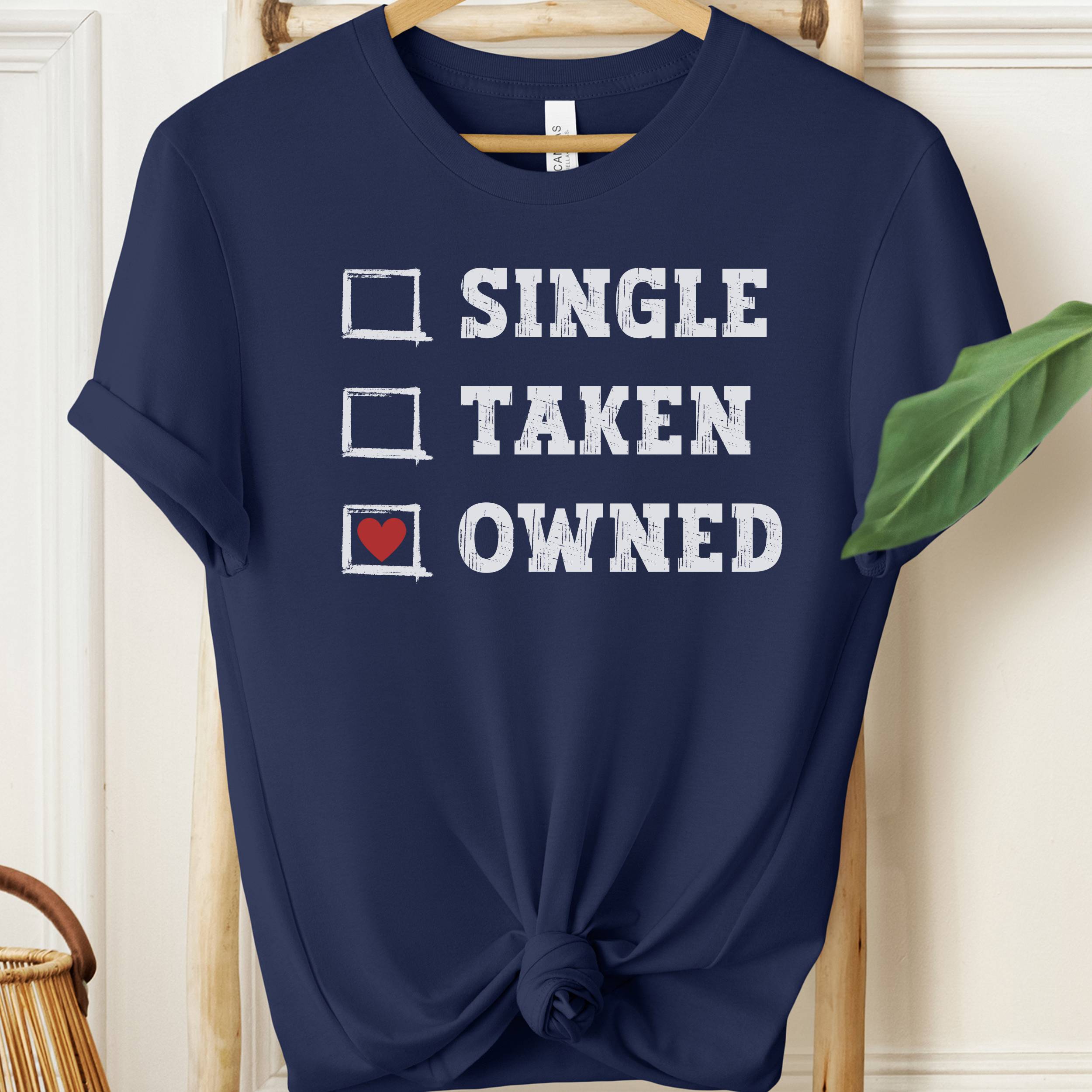 Navy blue t-shirt with humorous text design on a wooden hanger.