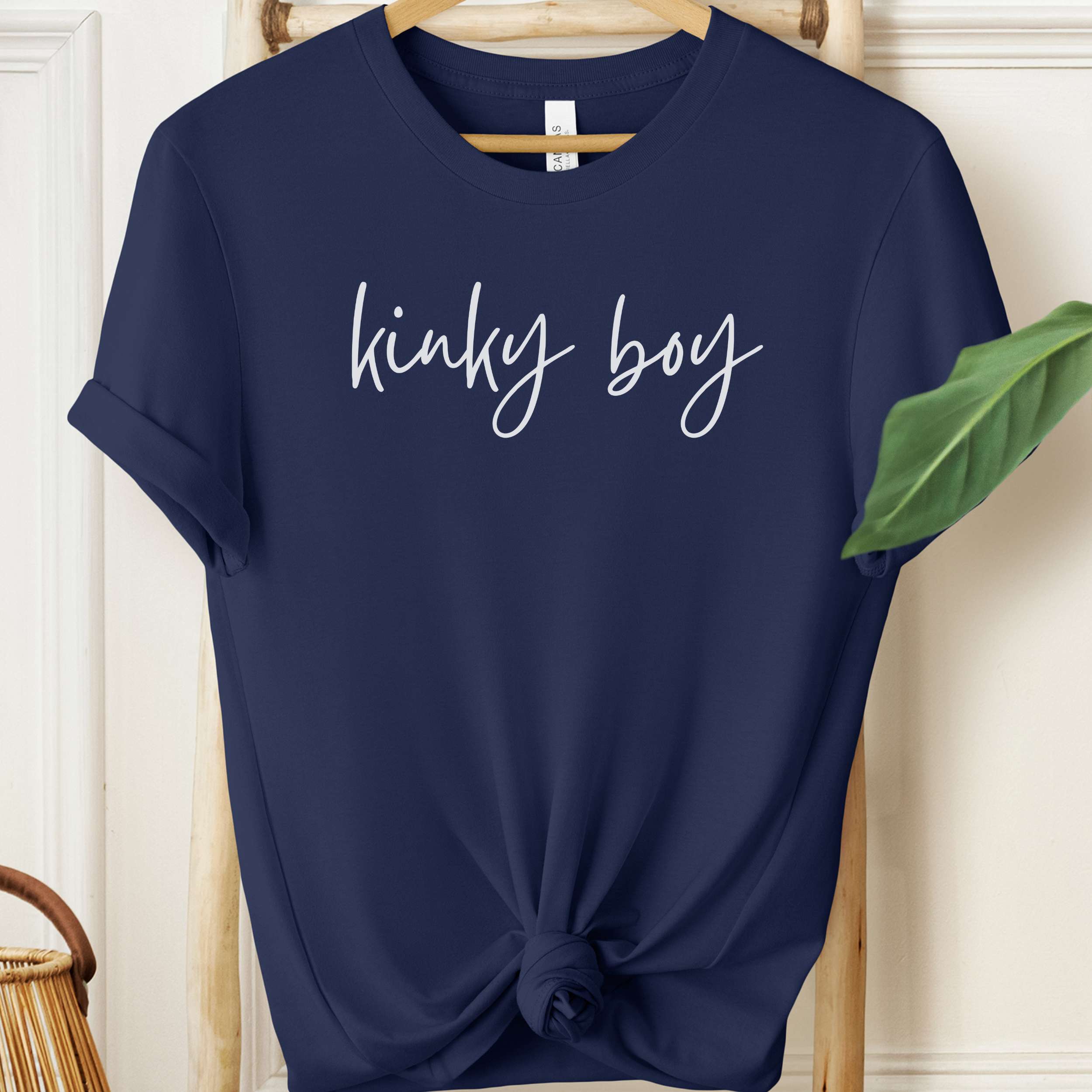 Navy blue t-shirt with 'kinky boy' text on a hanger against a neutral background