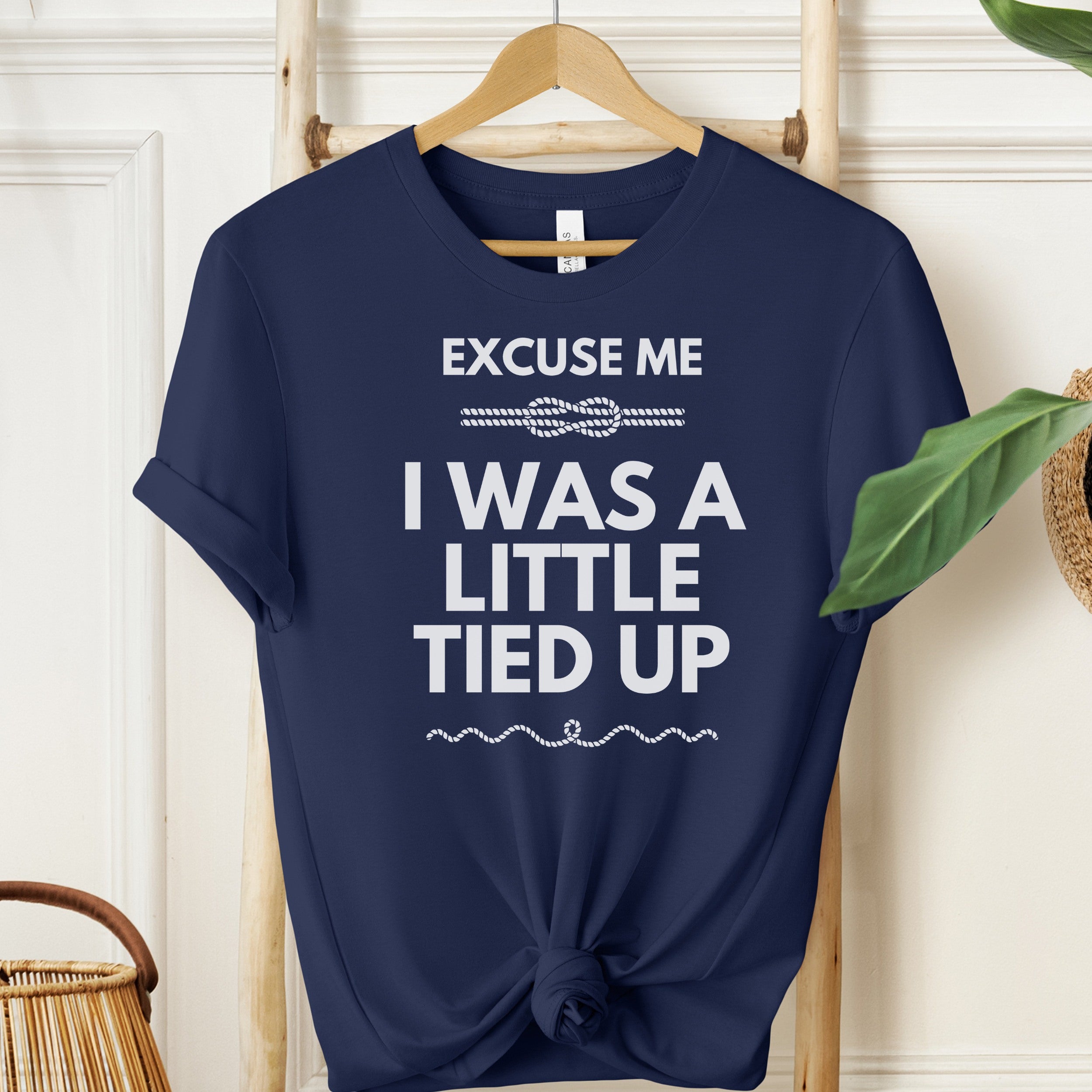 Navy blue t-shirt with white text on a wooden hanger against a white wall.