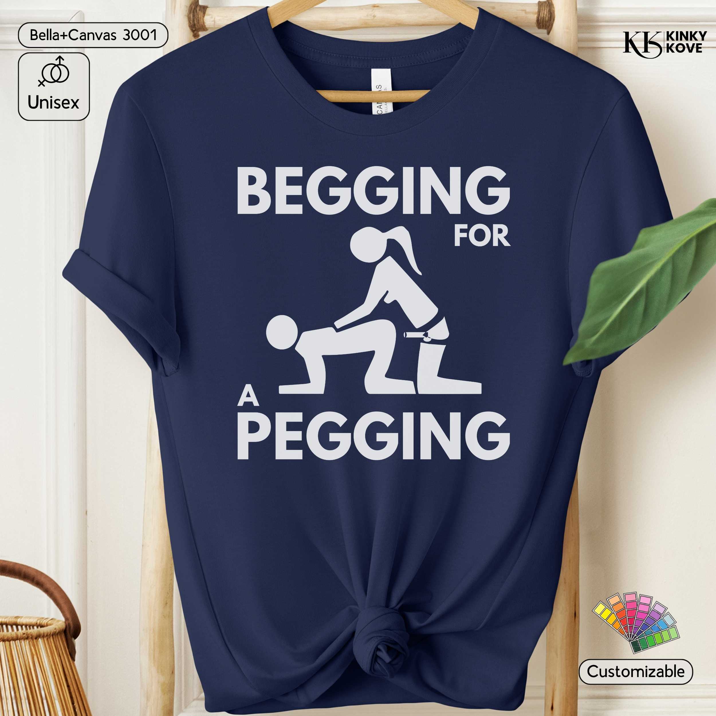 Navy blue t-shirt with white graphic and text 'Begging for a Pegging' on a hanger.