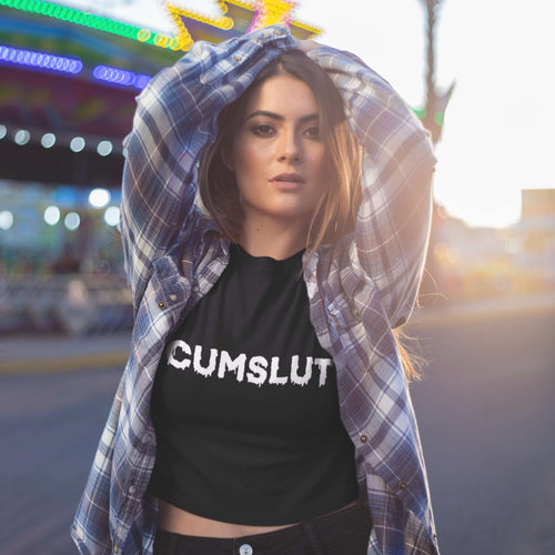 Woman wearing a black t-shirt with 'CUMSLUT' text at an amusement park.