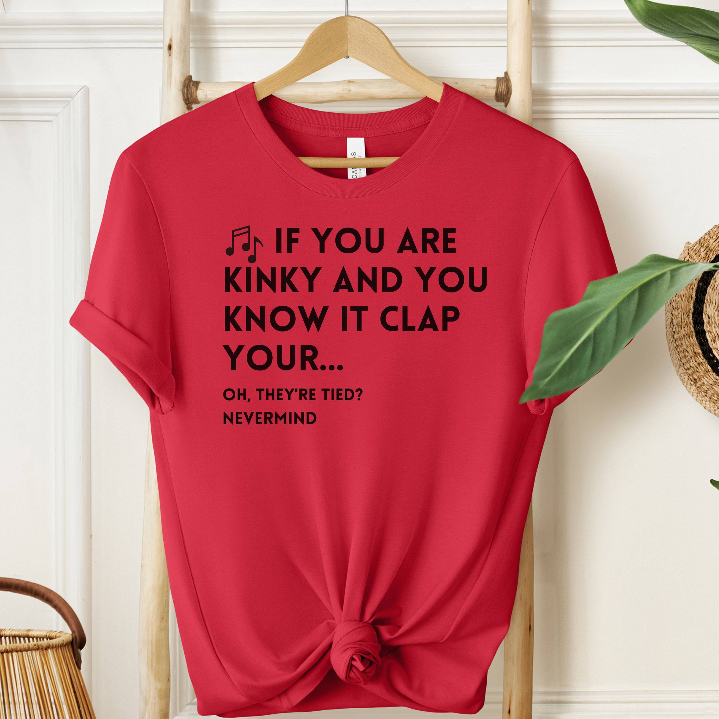 Red t-shirt with humorous text design on a wooden hanger against a white wall.