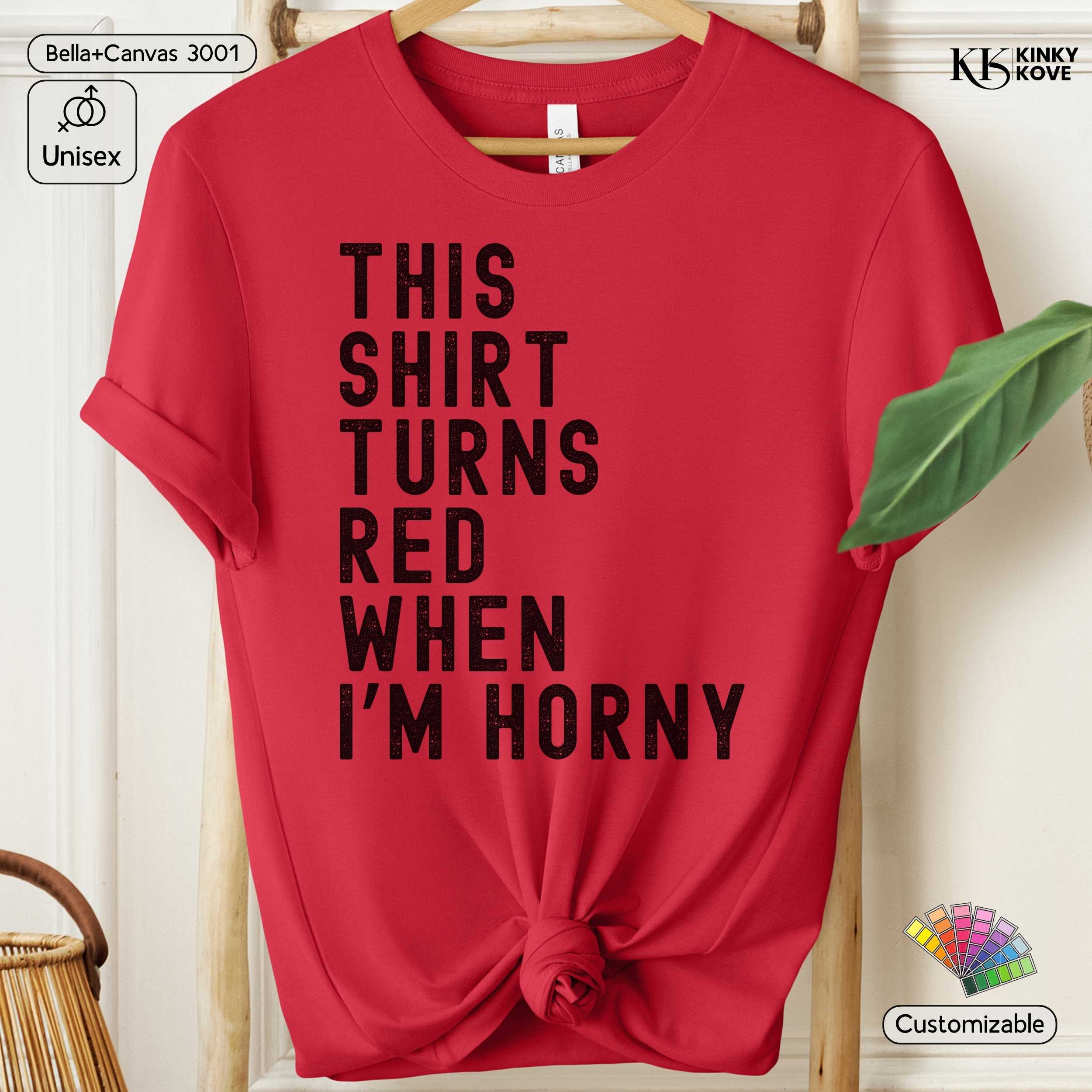Red t-shirt with black text 'This shirt turns red when I'm horny' on a hanger.