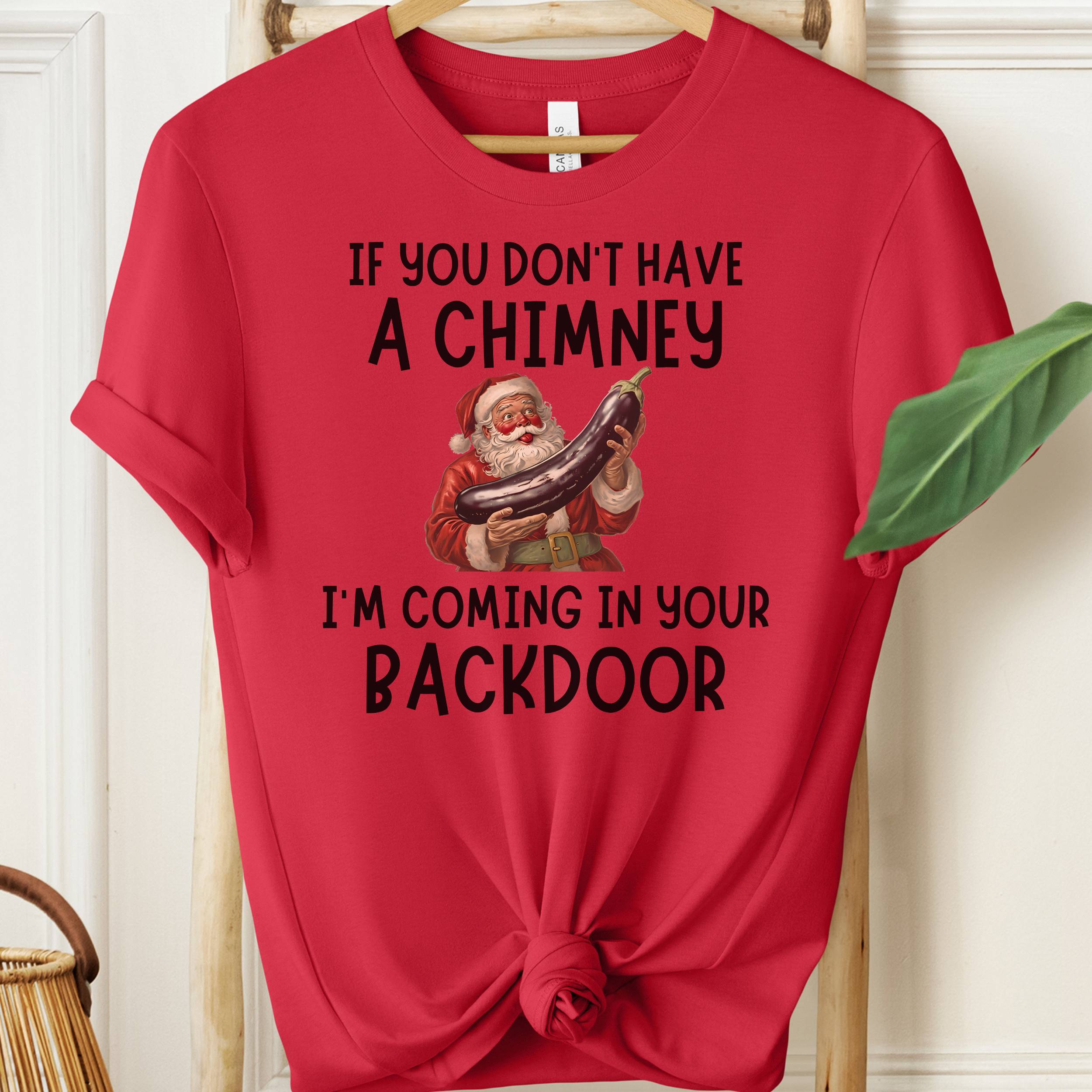 Red t-shirt with humorous Santa Claus graphic and text on a hanger.