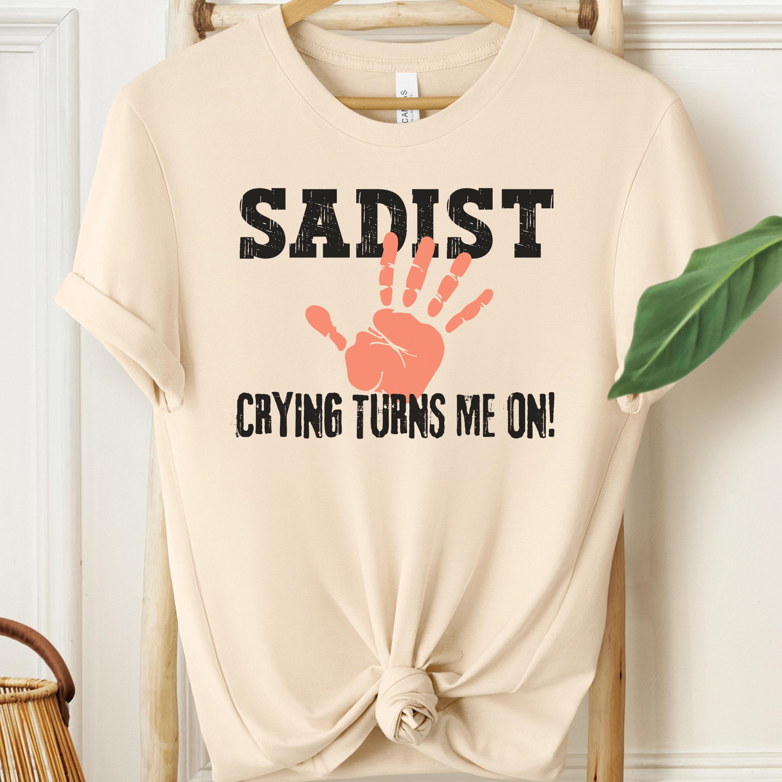 Soft cream kinky graphic tee with sadist text and orange handprint artwork