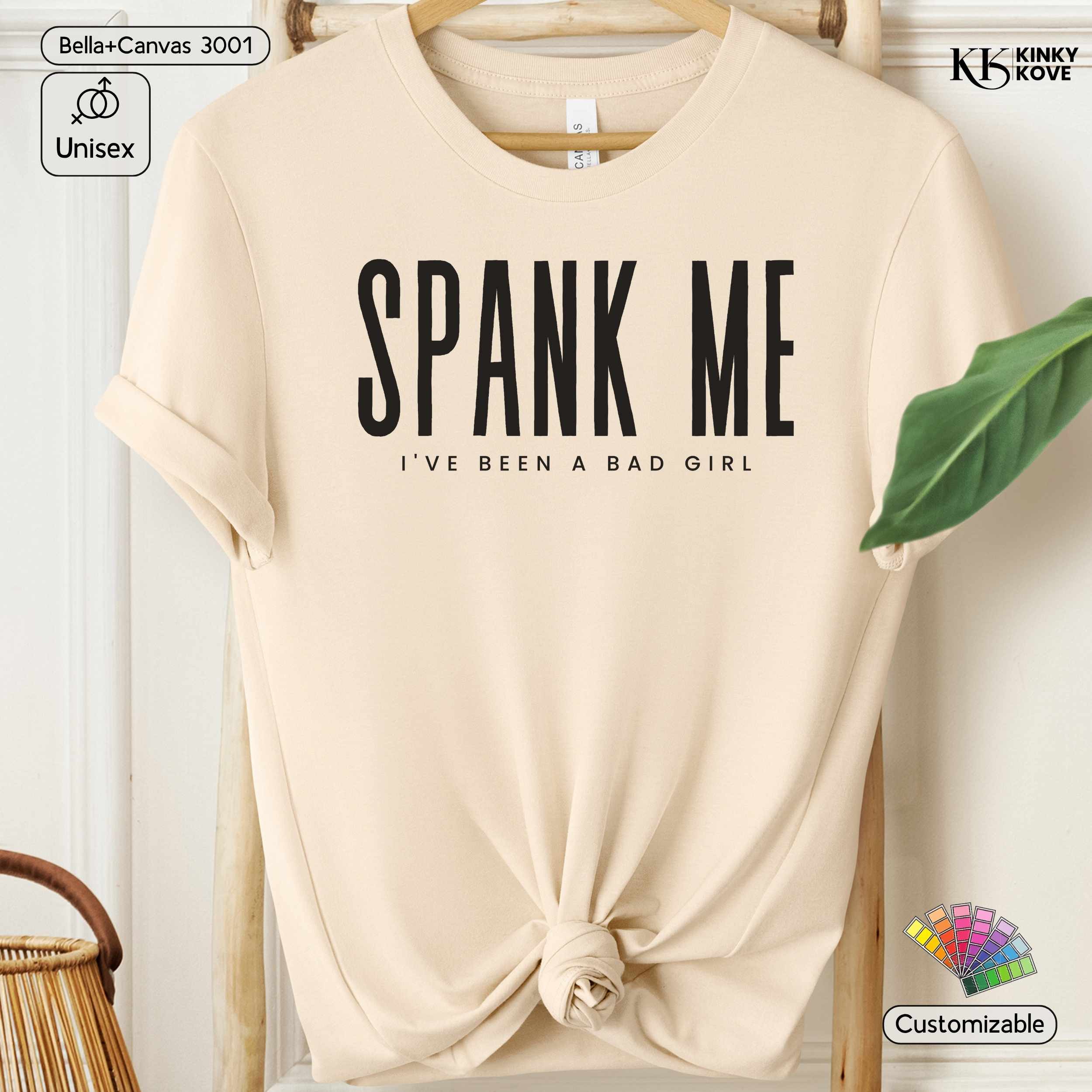 Beige t-shirt with 'SPANK ME I've Been a Bad Girl' text on a hanger.