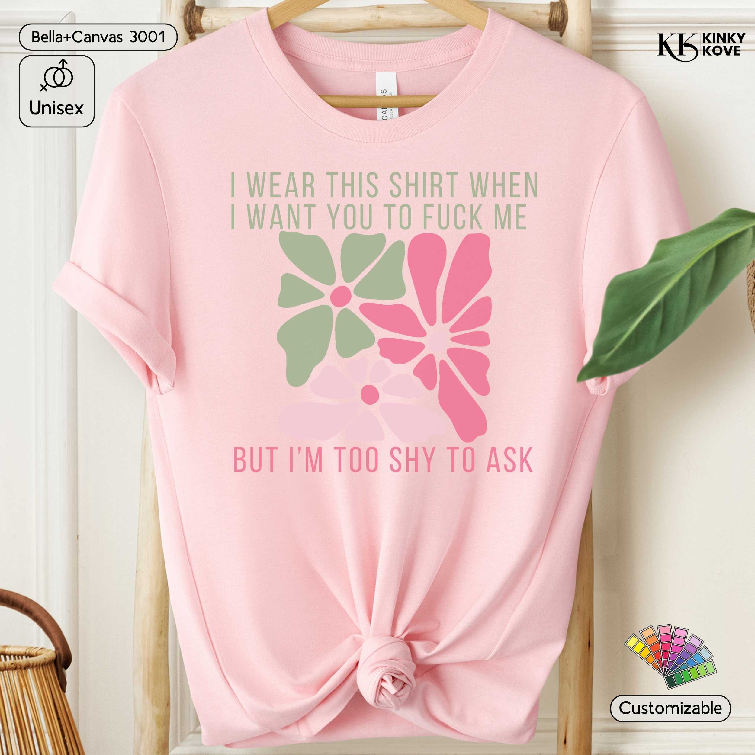 Pink t-shirt with graphic design and text on a hanger