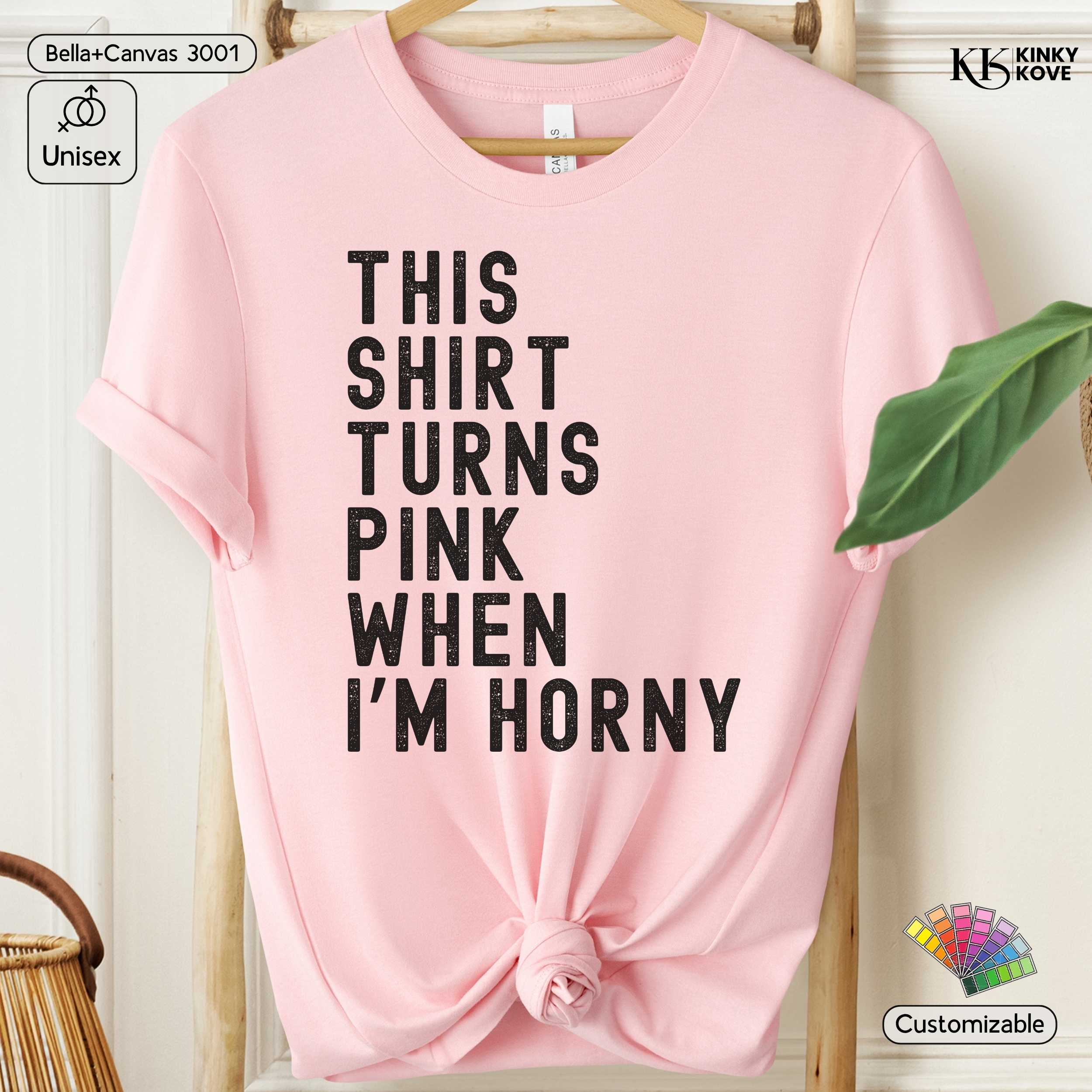 Pink t-shirt with text 'This shirt turns pink when I'm horny' on a hanger.