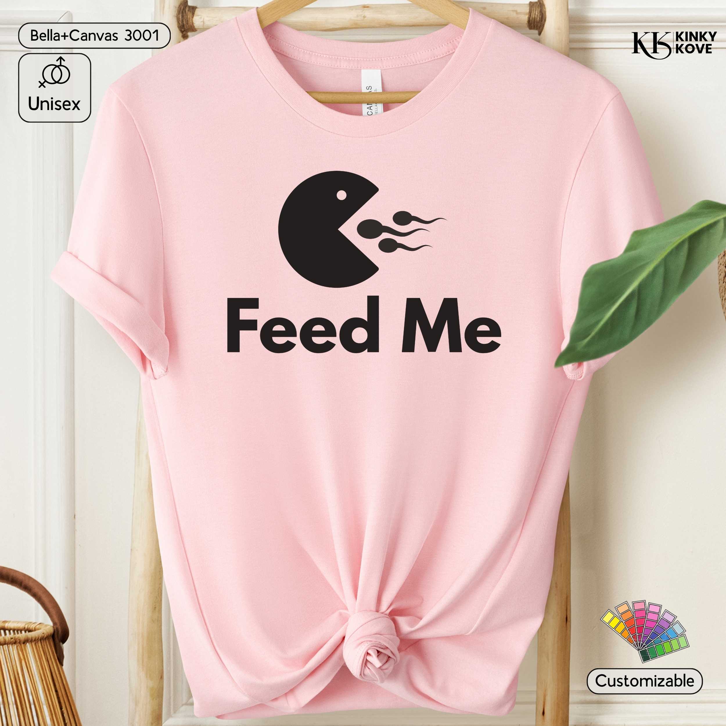 Pink t-shirt with 'Feed Me' graphic design on a hanger
