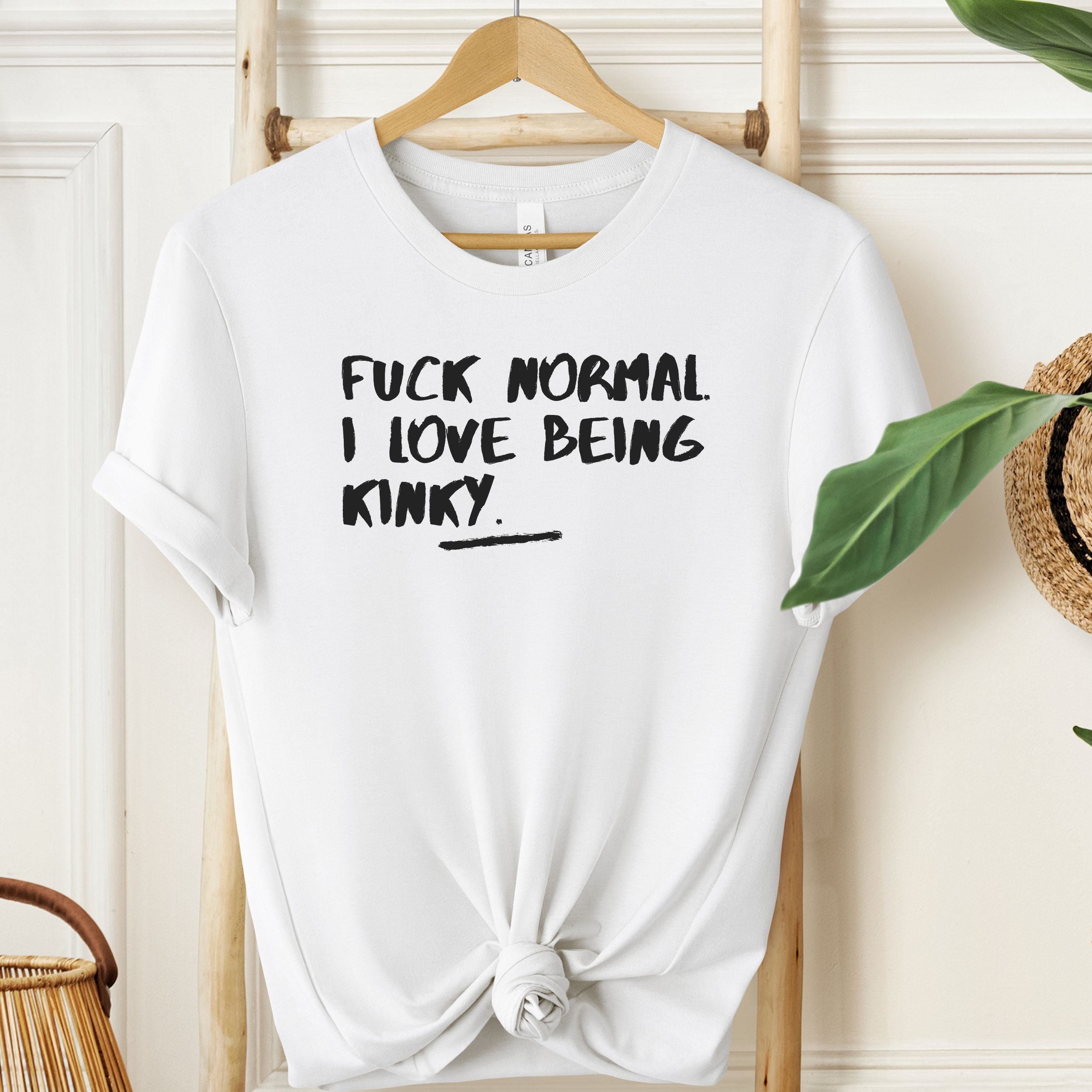 White t-shirt with black text on a hanger against a neutral background