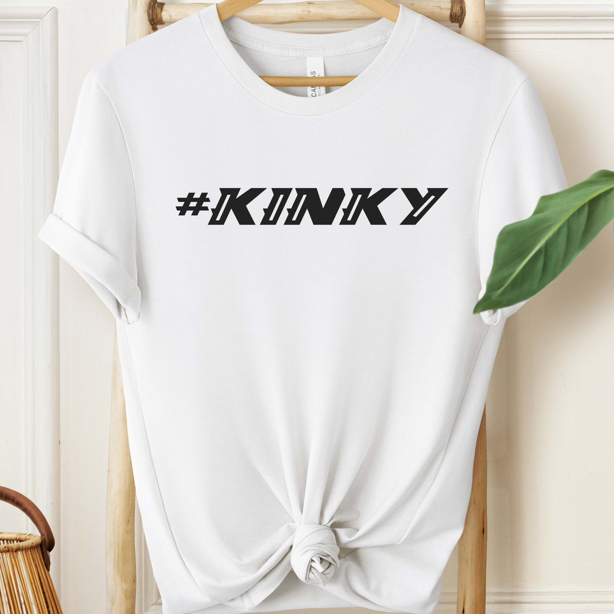 White t-shirt with '#KINKY' text on a hanger against a neutral background